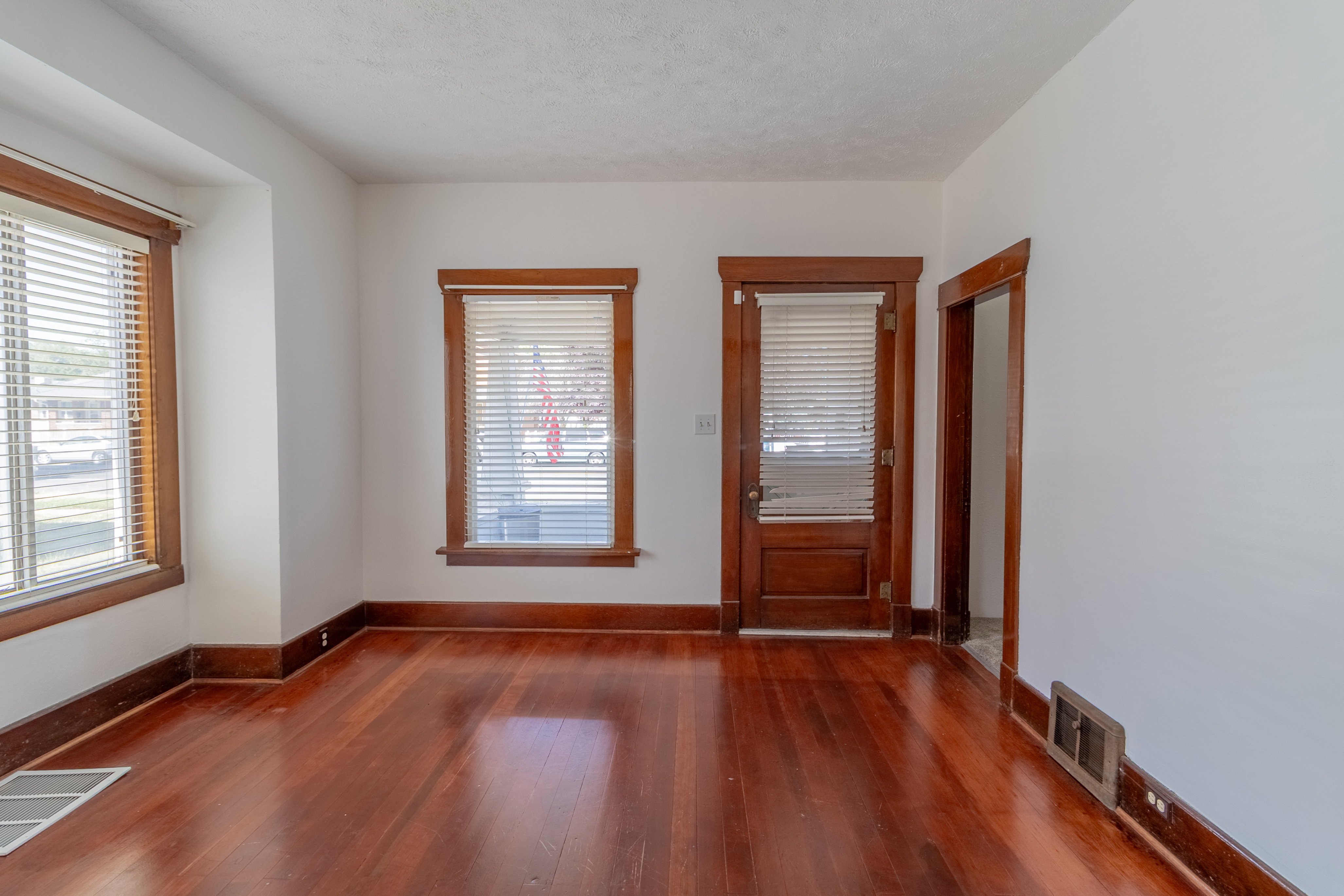 Hardwood flooring throughout featuring white walls and dark wood-finish trim