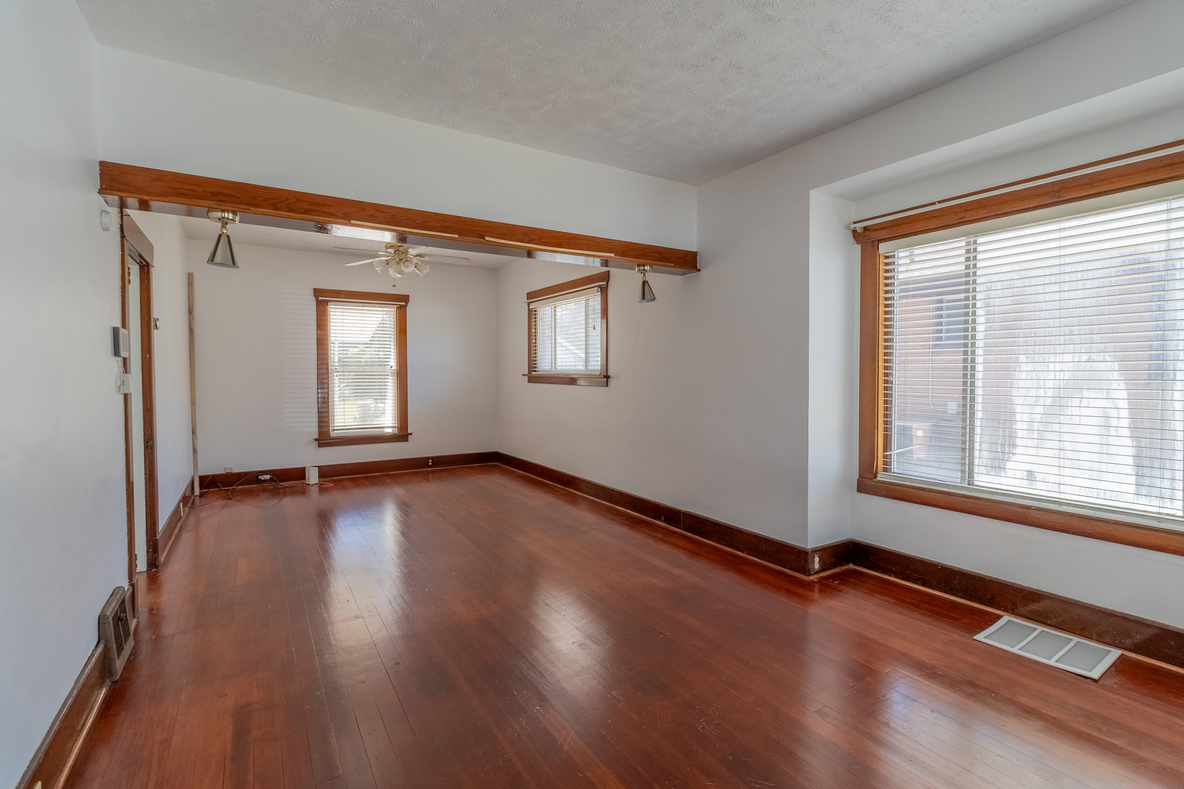 Spacious interior room featuring rich wood-finish flooring, white walls, and prominent wood trim