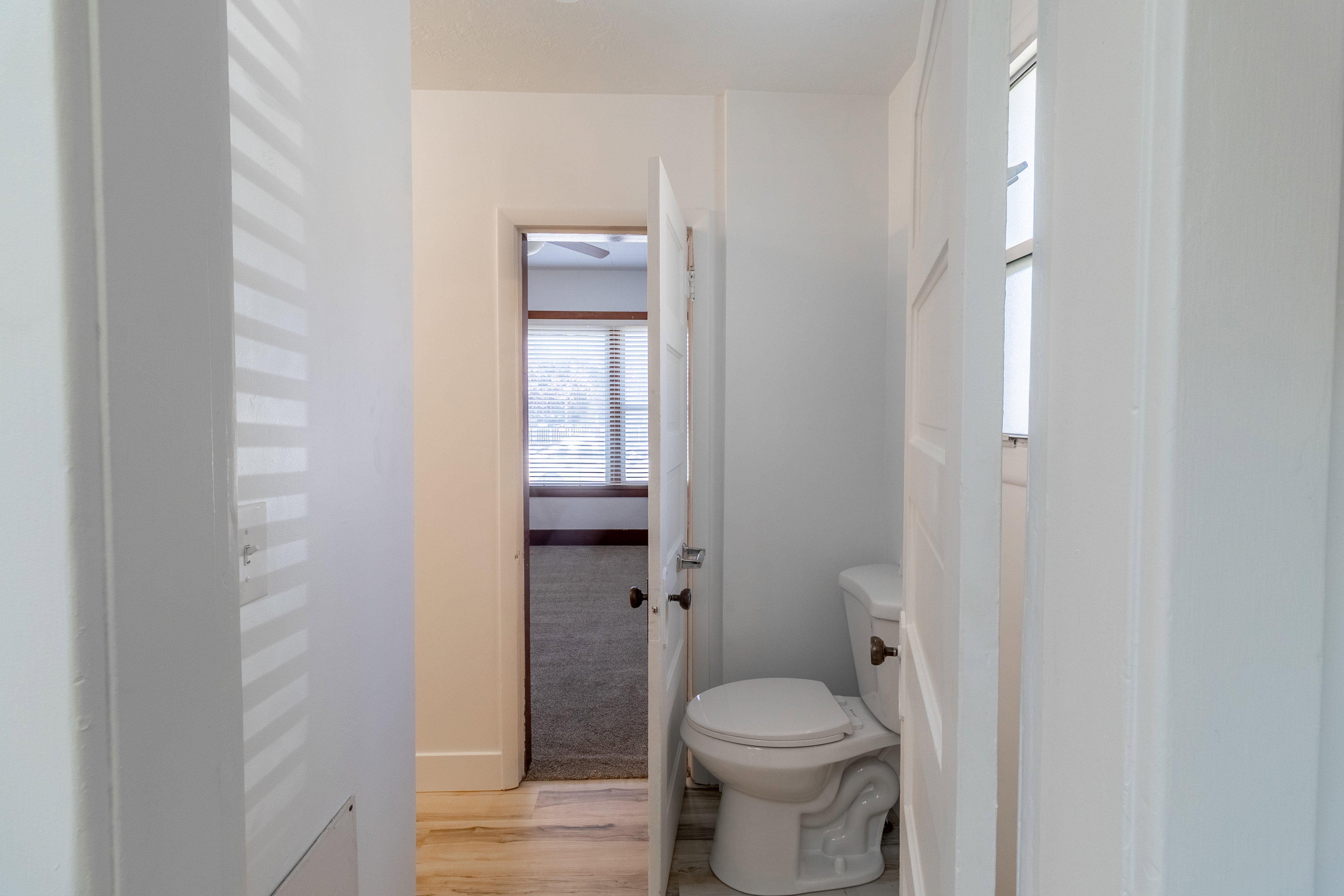 Hallway featuring light wood-finish flooring and a white paneled door