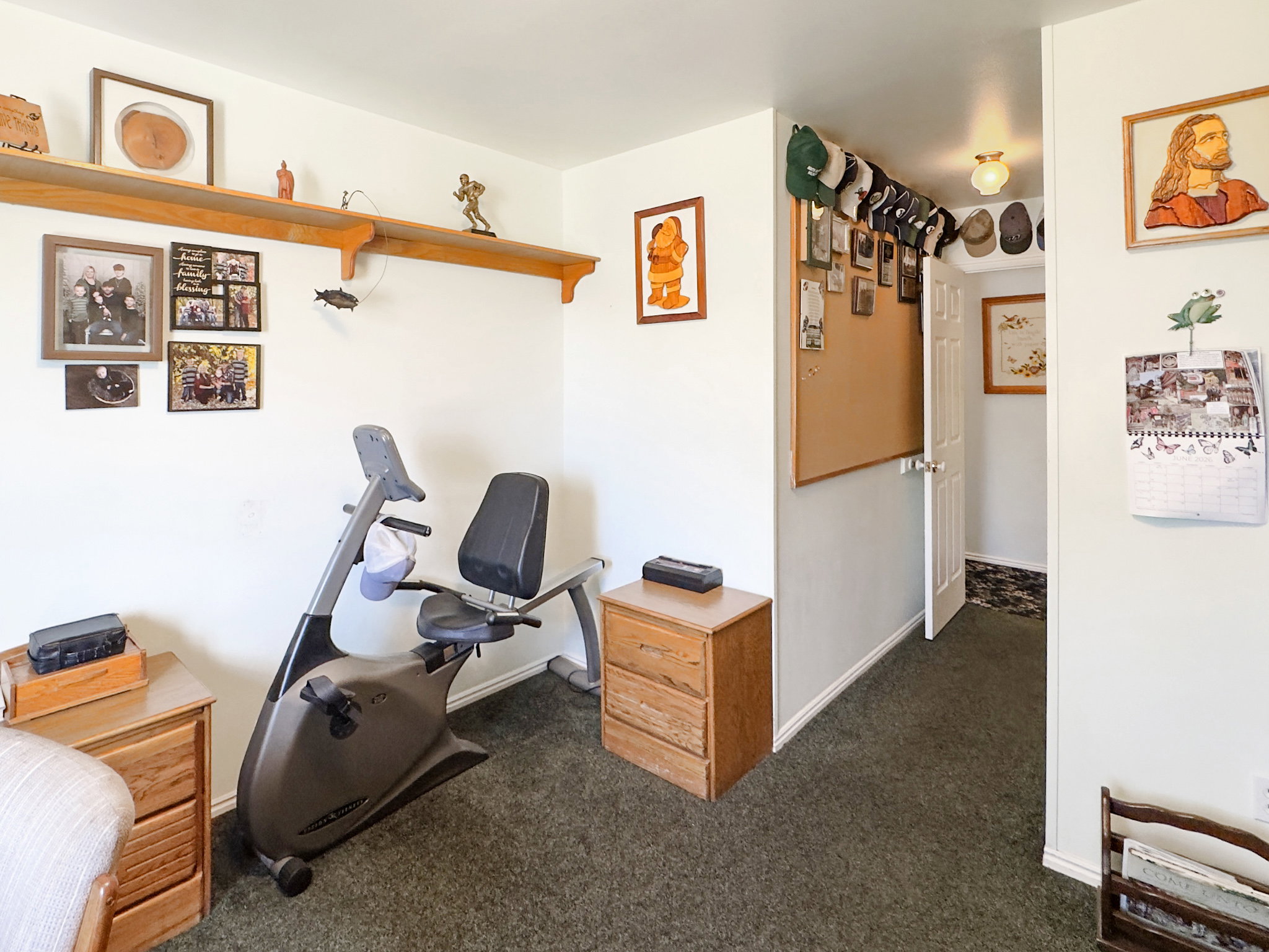 Bright interior room featuring a long wall-mounted wooden shelf, light-colored walls, and green carpet flooring