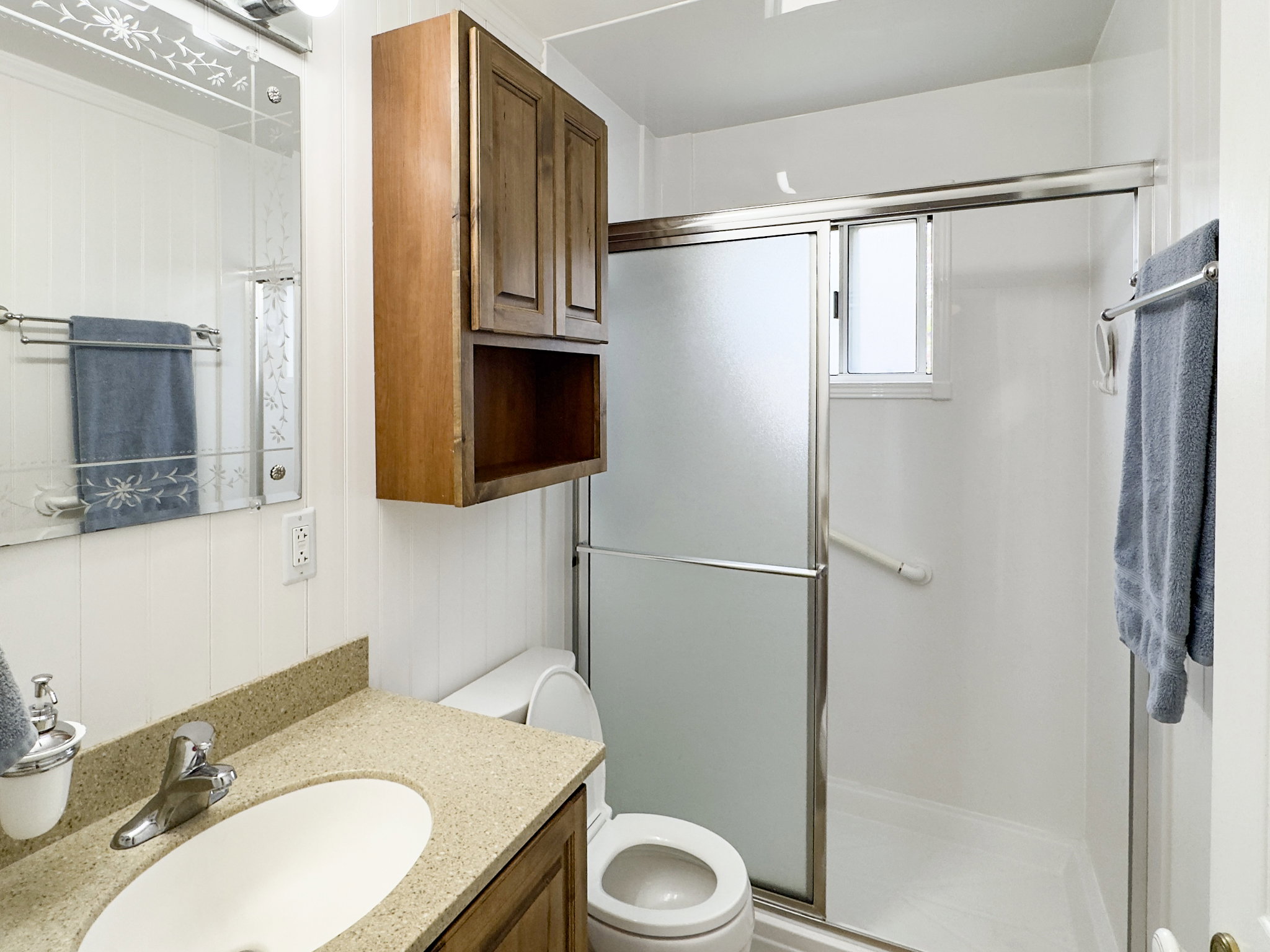 Bathroom featuring a shower with sliding frosted glass doors, a window, and a grab bar