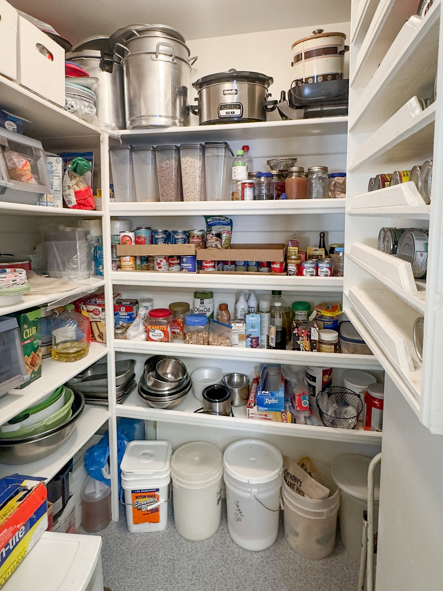 Built-in pantry shelving featuring white wood construction, floor-to-ceiling storage, and integrated can organizers