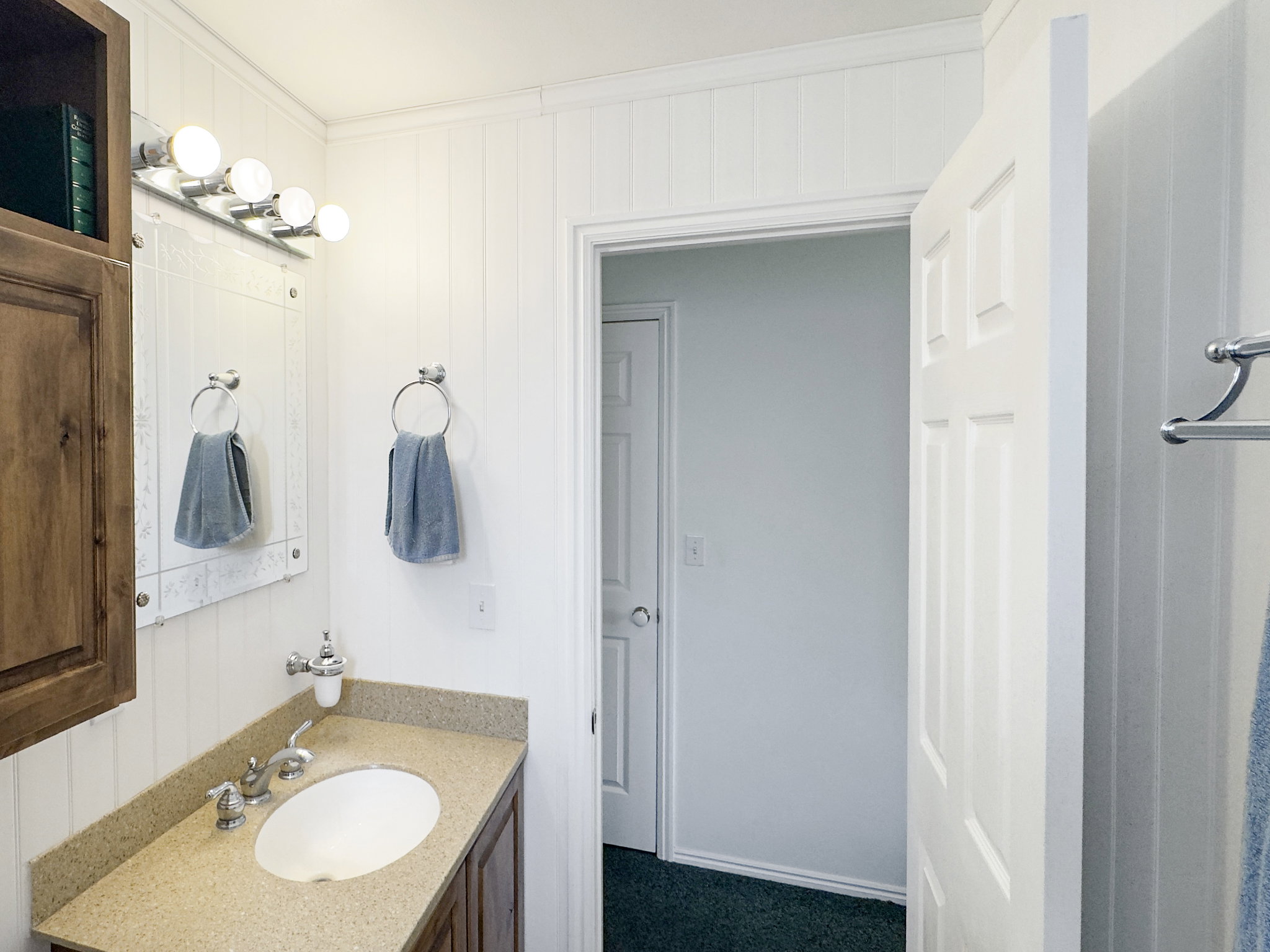 Bathroom featuring a vanity with an oval undermount sink, a flecked countertop, and wood-finish cabinetry