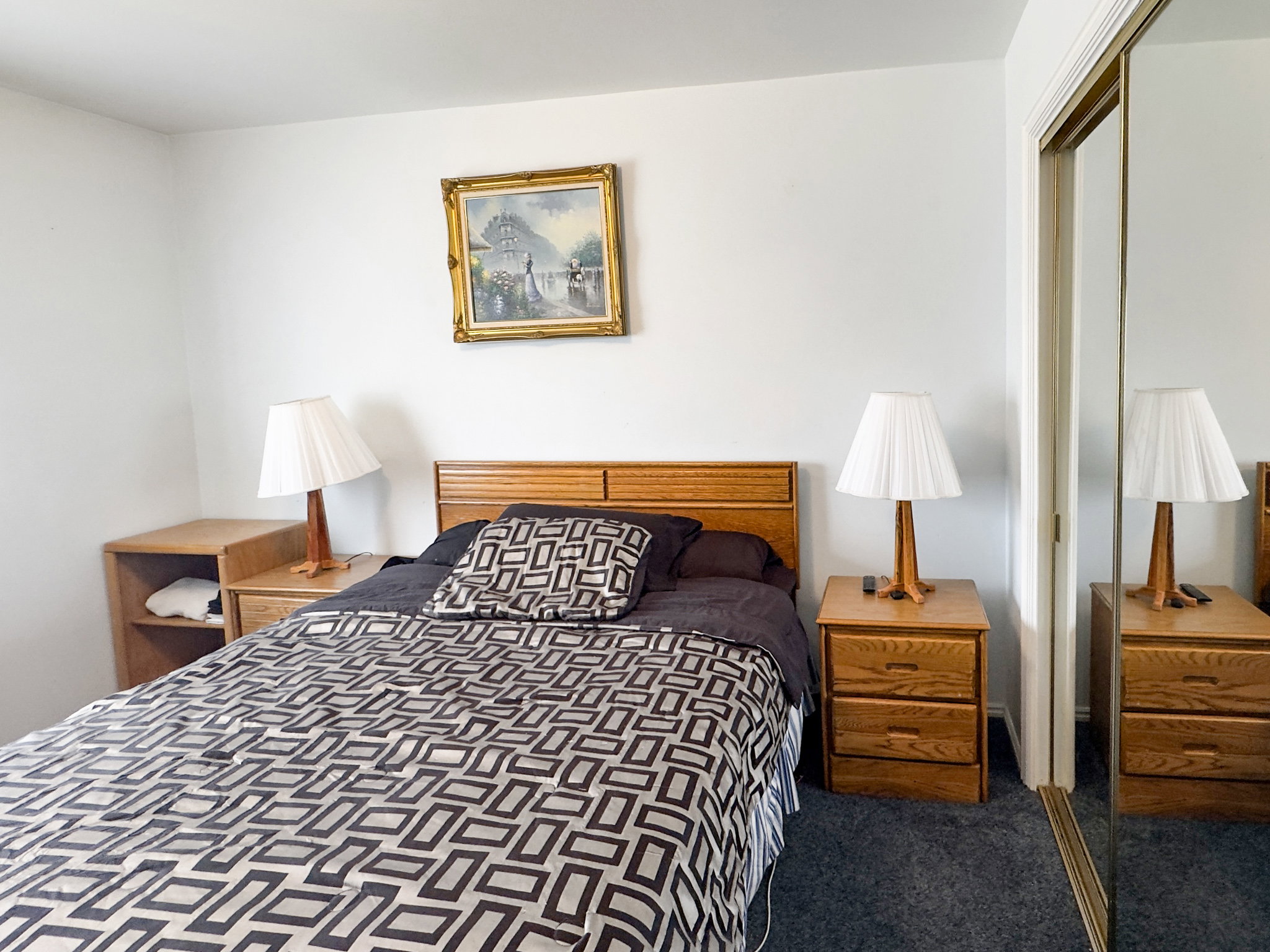 Bedroom featuring neutral wall paint, gray carpet flooring, and a sliding mirrored closet door