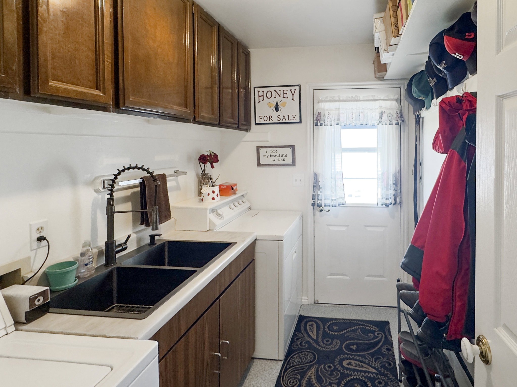 Laundry area featuring a double basin sink with matte black faucet, wood-finish cabinetry, and a white countertop