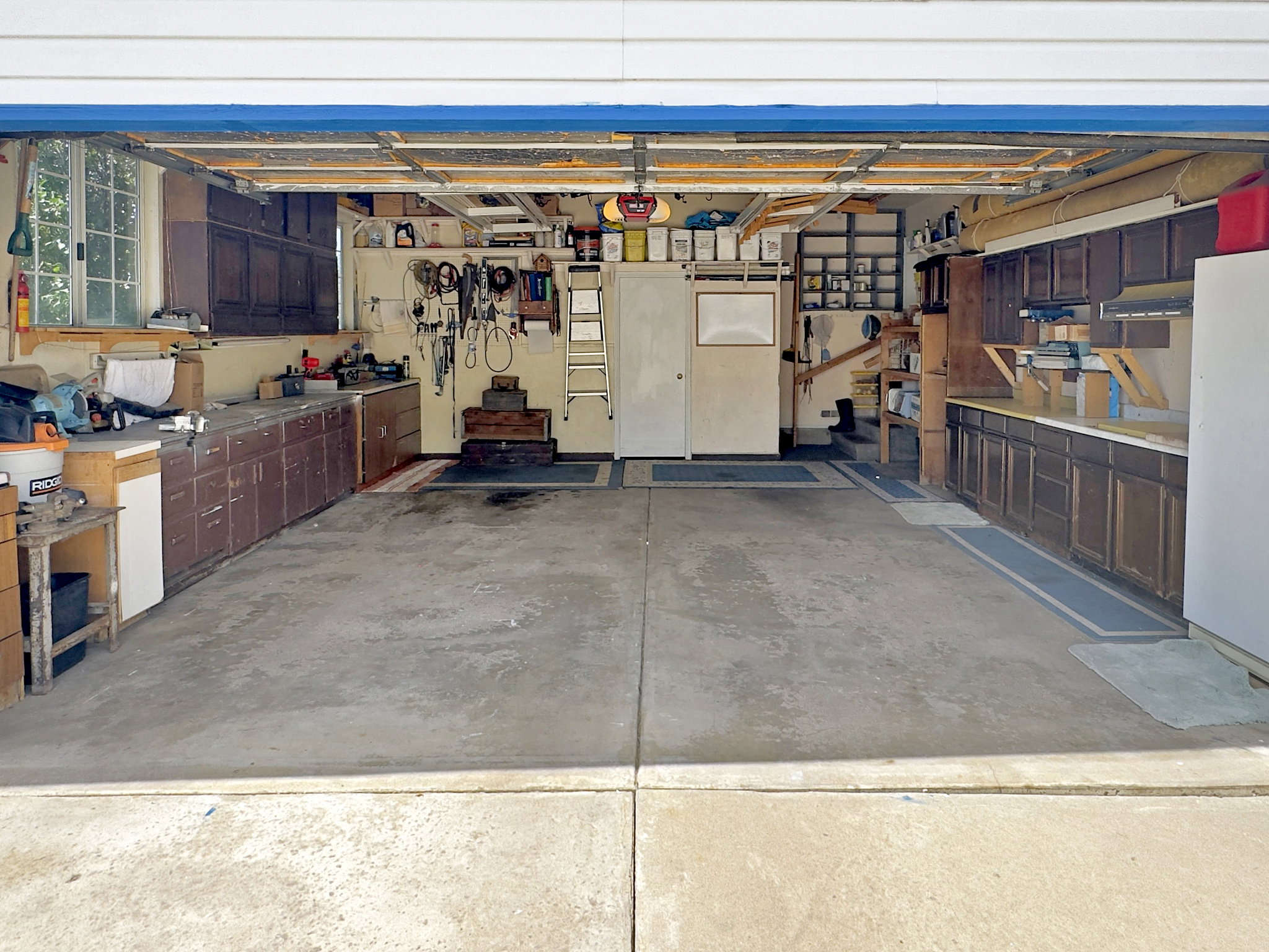 Spacious two-car garage featuring a concrete floor, built-in cabinetry, and a window for natural light