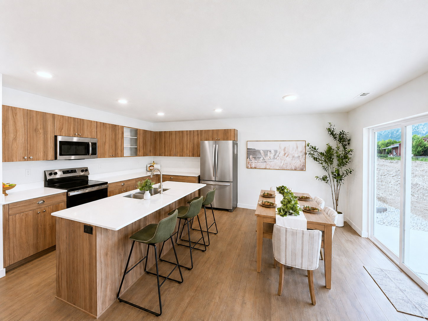 Spacious kitchen and dining area featuring wood-finish cabinetry, white countertops, stainless steel appliances, and a central island with bar seating