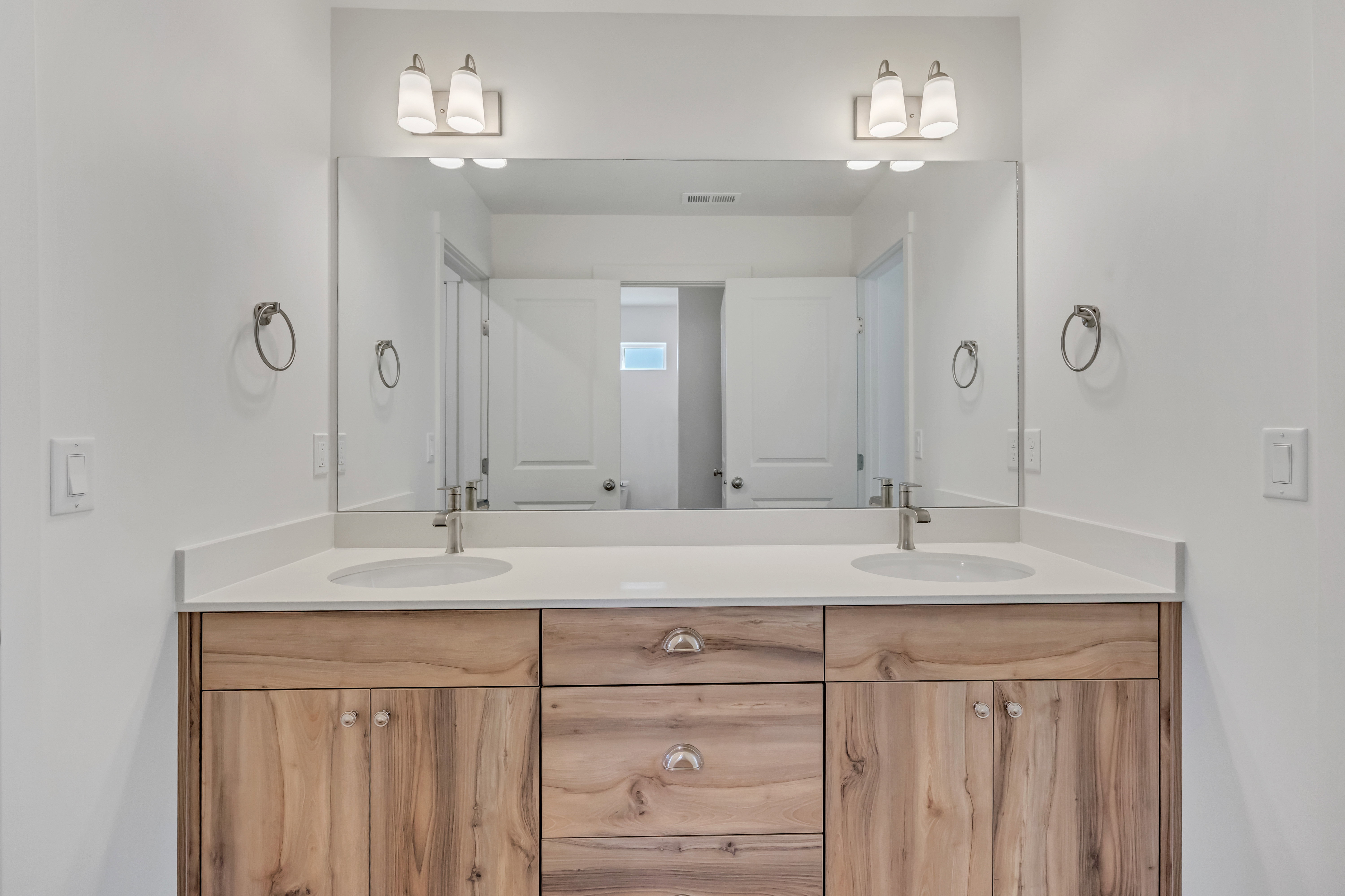 Dual vanity featuring wood-finish cabinetry, white countertops, and undermount sinks
