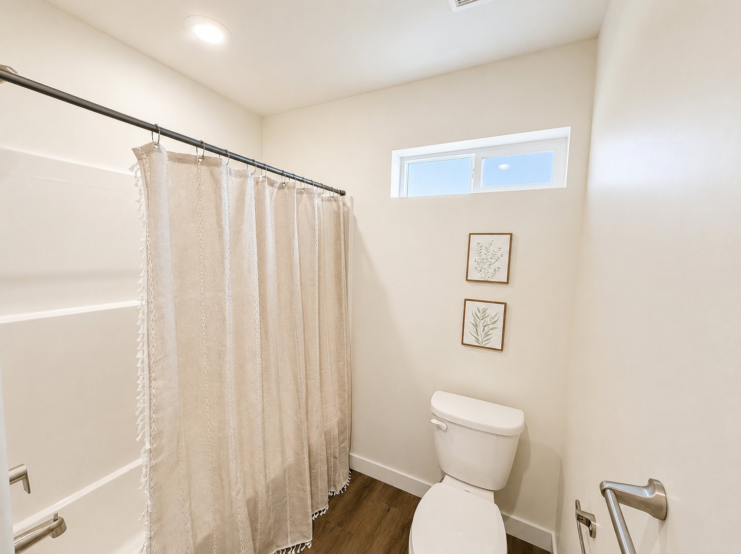 Bathroom featuring a white bathtub, wood-finish flooring, and a high horizontal window