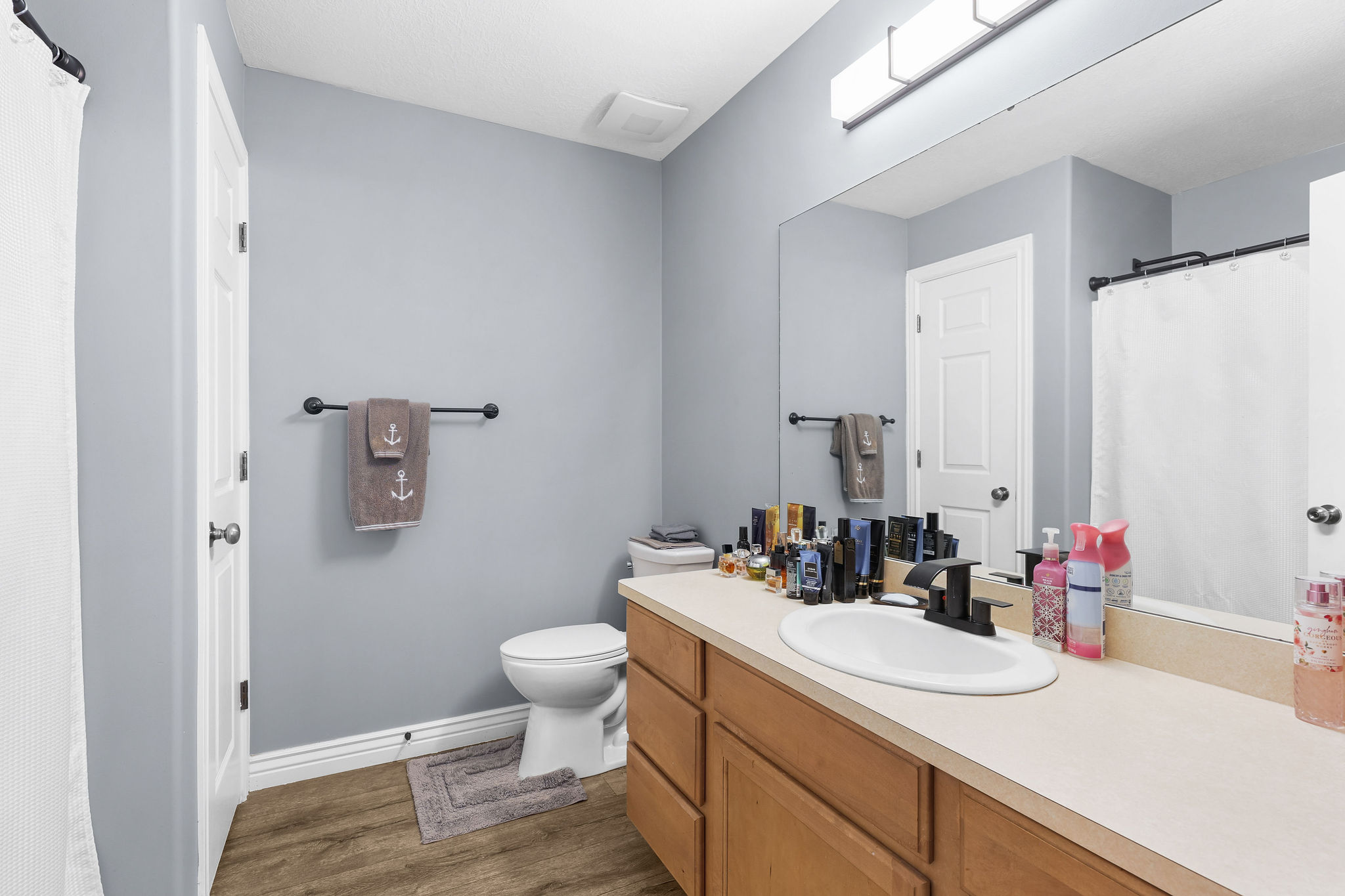 Bathroom featuring a wood-finish floor, light blue walls, and a light wood vanity with a light-colored countertop