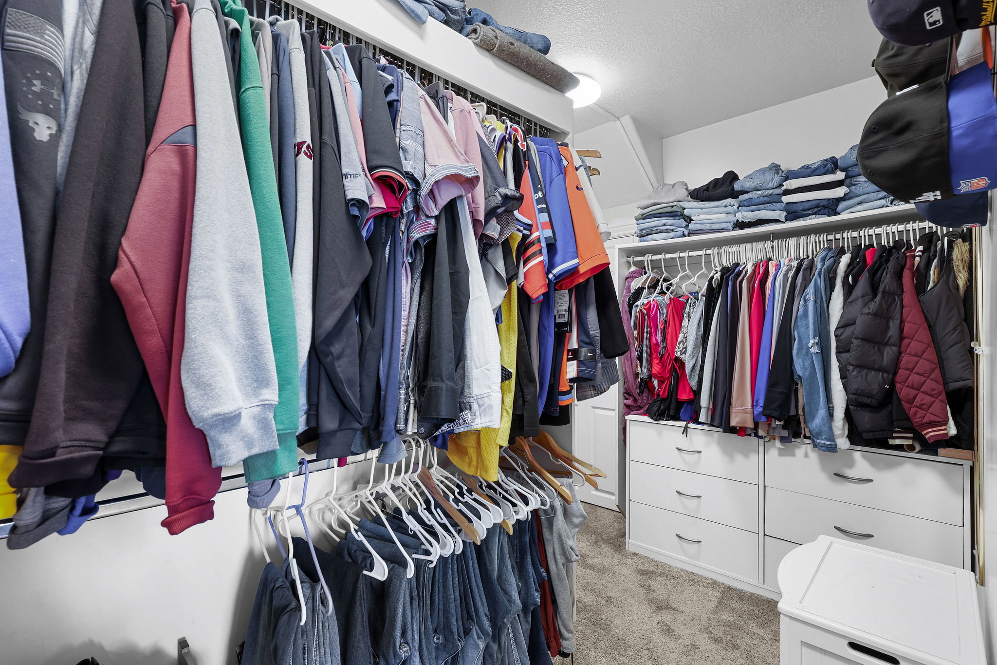 Walk-in closet featuring white built-in cabinetry, chrome hanging rods, recessed lighting, and carpet flooring