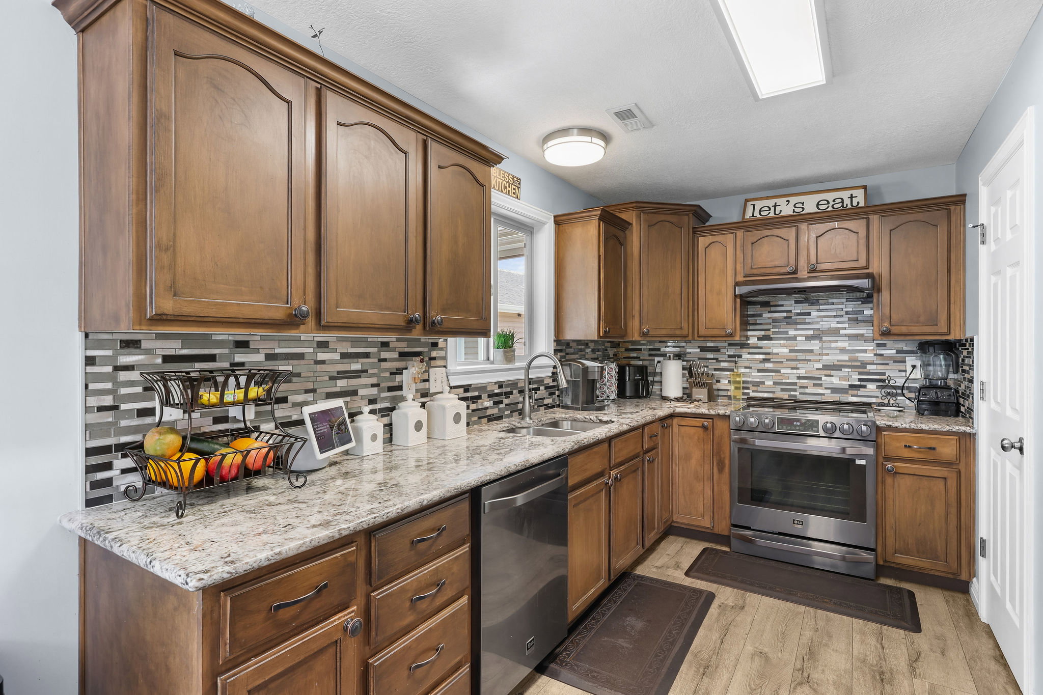 Kitchen featuring rich wood-finish cabinetry, light-toned granite countertops, and a modern tile backsplash