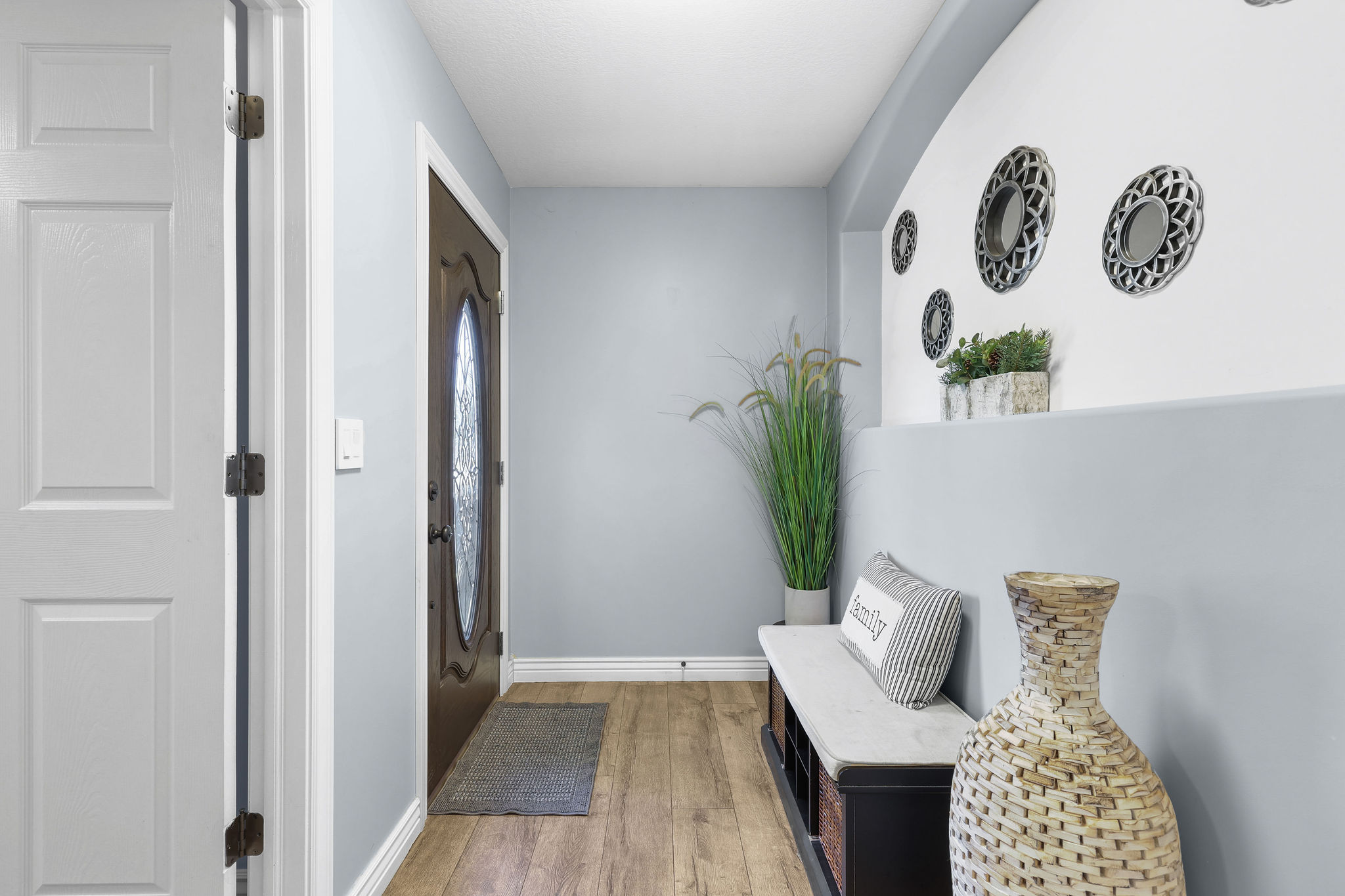 Entryway featuring wood-finish flooring, a paneled interior door, and a dark-stained front door with an oval-shaped decorative glass insert