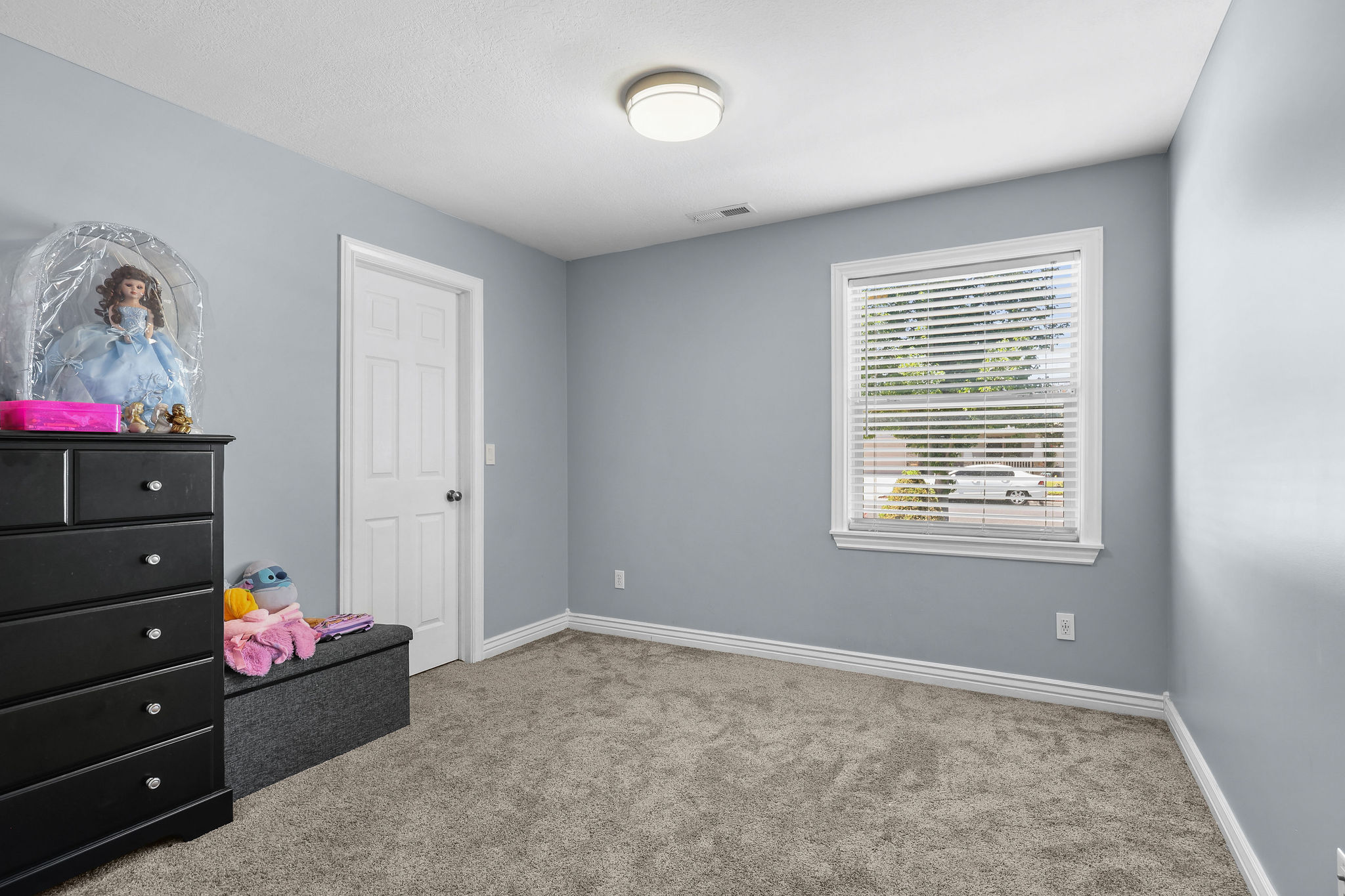 Carpeted room with a single window featuring white blinds and trim