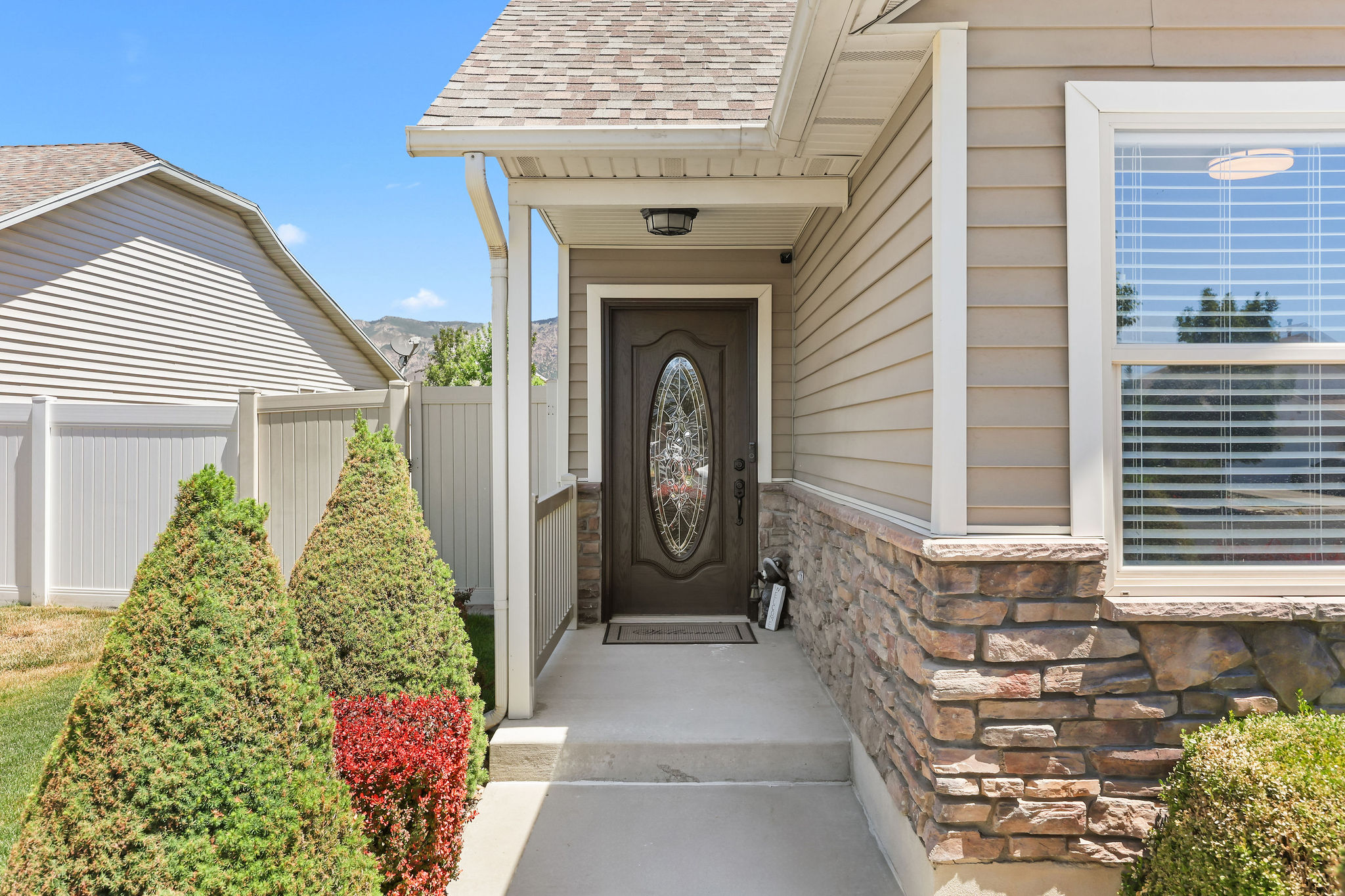 Front entry featuring a decorative glass door, stone veneer accents, and horizontal siding