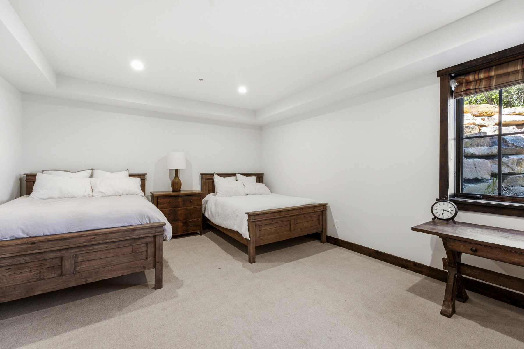 Spacious room featuring two wood-frame beds, a wood nightstand, and a built-in window with dark wood trim