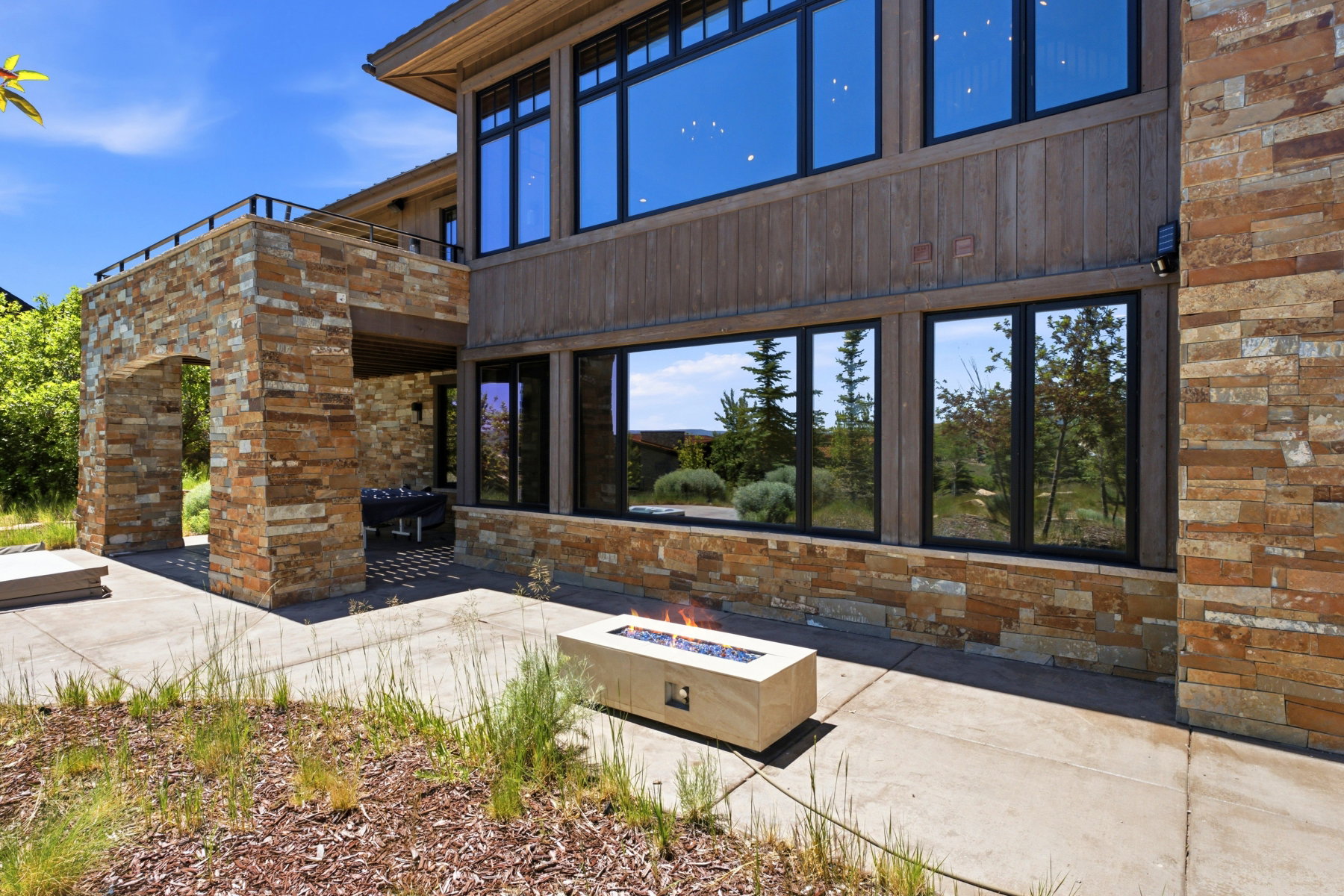 Exterior stone and wood-paneled facade with large black-framed windows