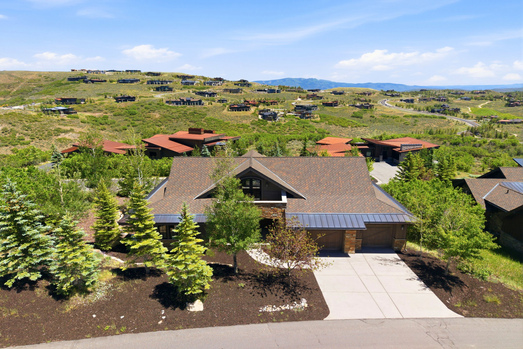 Contemporary residence featuring a multi-car garage, concrete driveway, and a stone and wood facade
