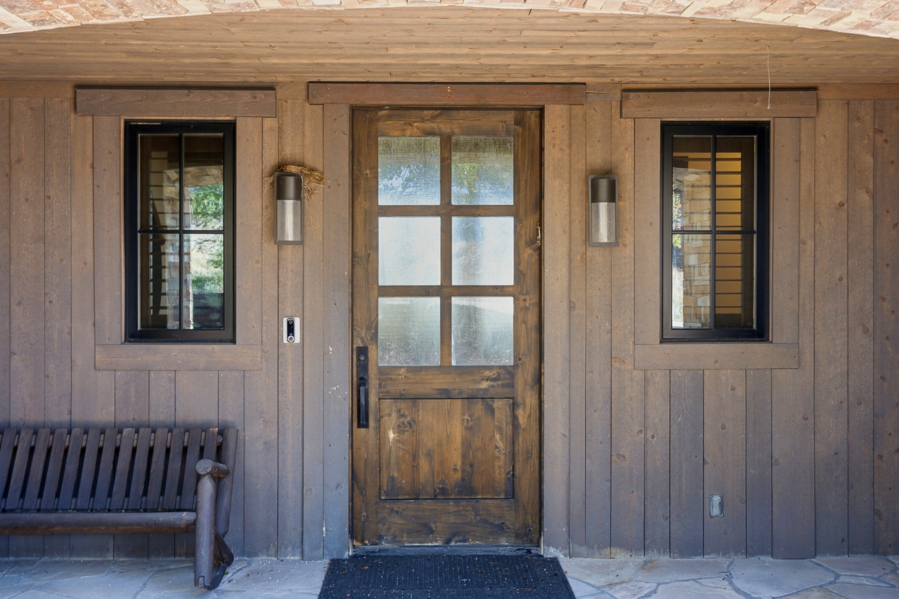 Rustic wood paneling exterior featuring a multi-pane wooden entry door with frosted glass