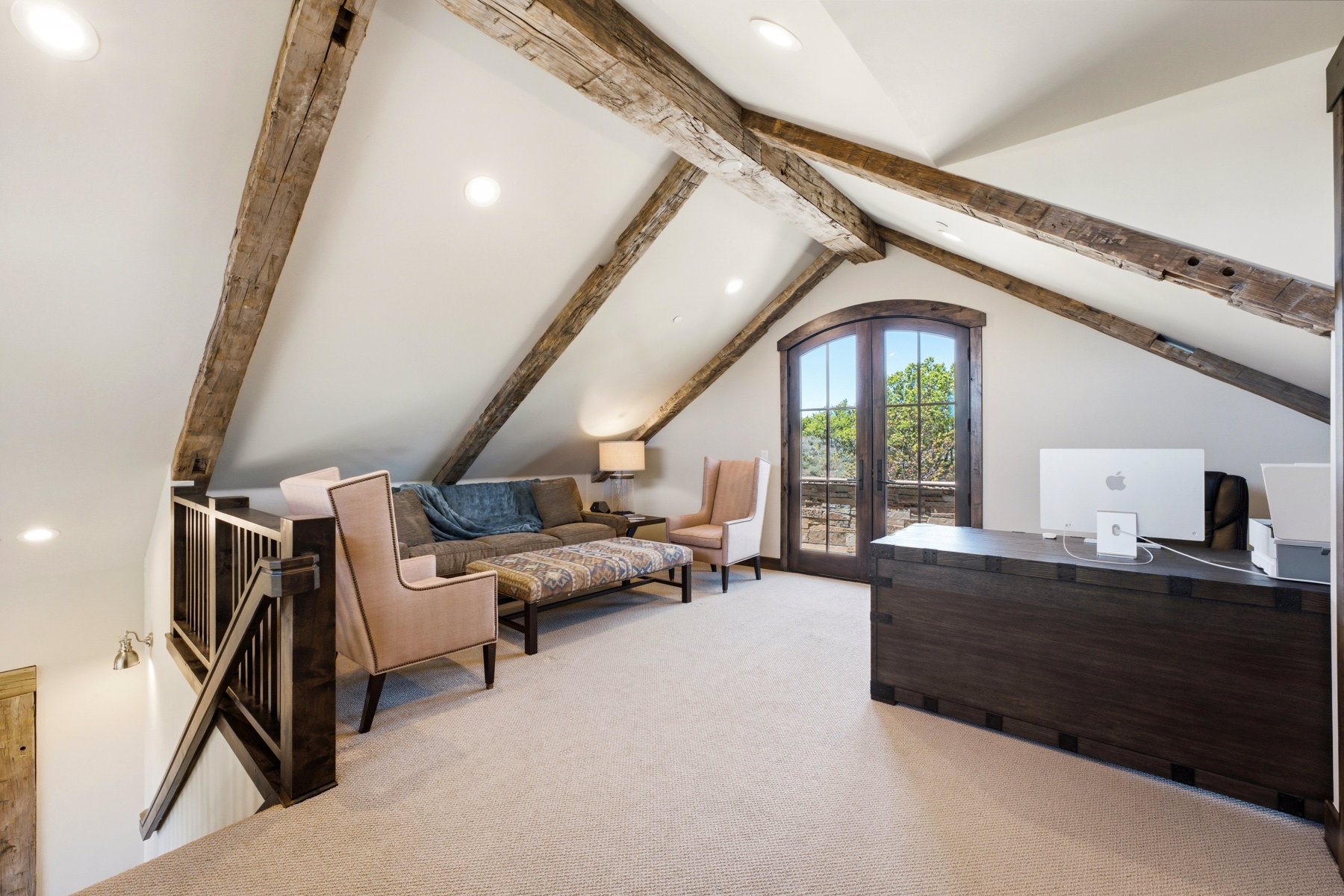 Vaulted ceiling with exposed wood beams, arched French doors, light-colored carpeting, recessed lighting, and dark wood railing