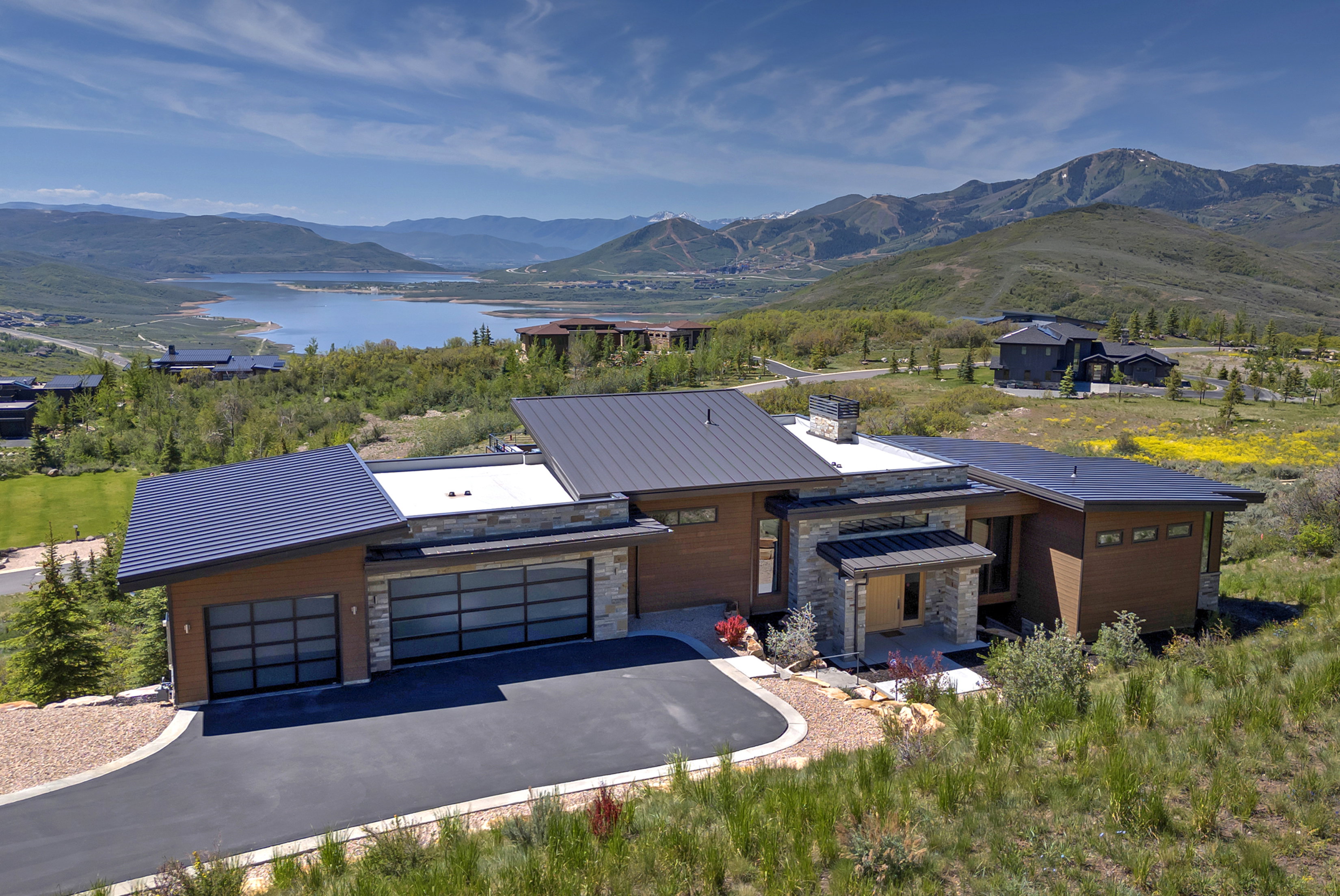 Modern architectural residence featuring a prominent metal roofline, natural wood-finish siding, and stone accents