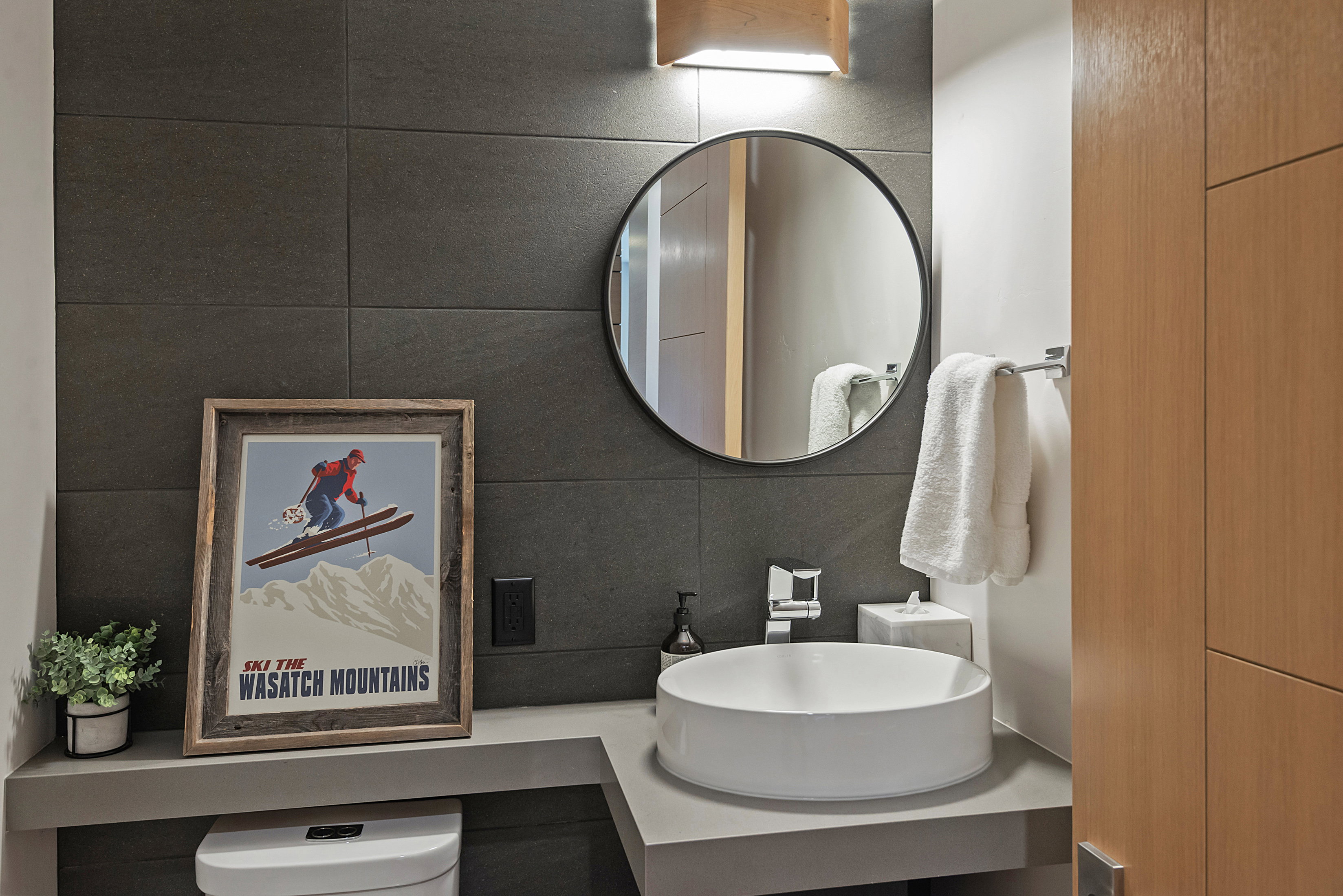 Contemporary bathroom featuring a circular vessel sink, wall-mounted faucet, and a round frameless mirror