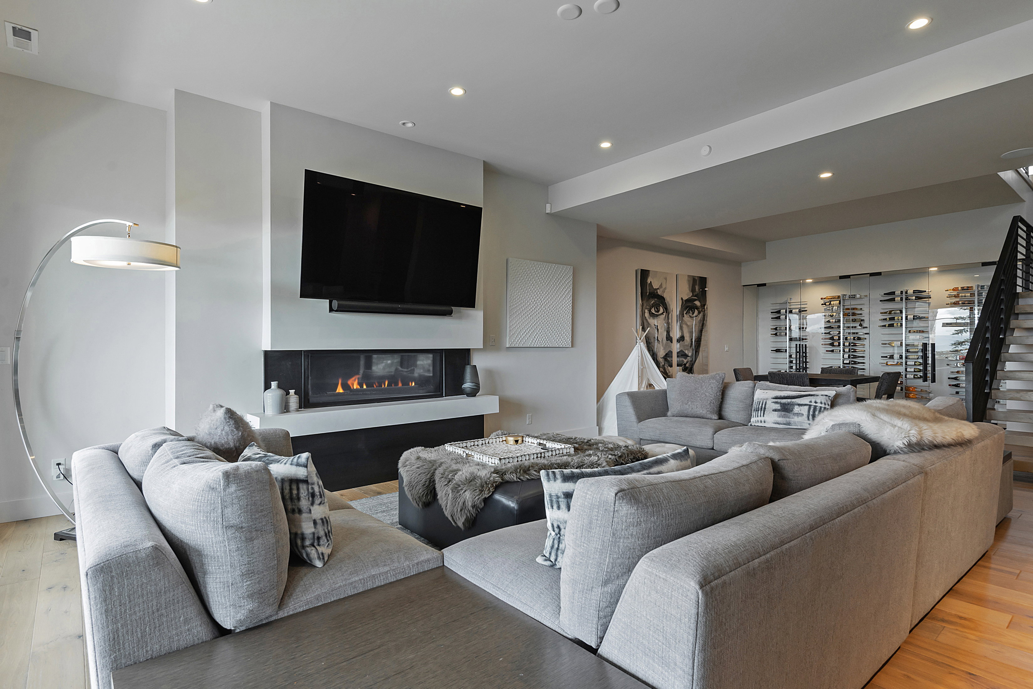 Open-concept living space featuring a modern linear gas fireplace with a white mantel, recessed lighting, and wood-finish flooring