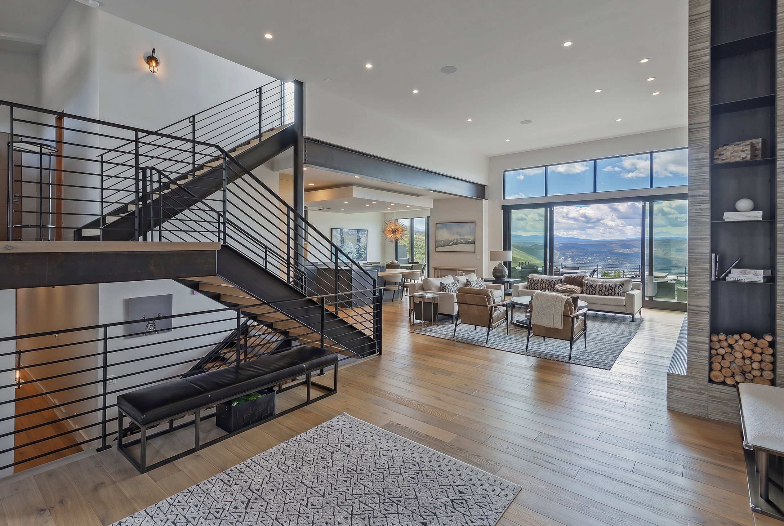 Contemporary interior with wood-finish flooring and a multi-level staircase featuring industrial-style metal railings