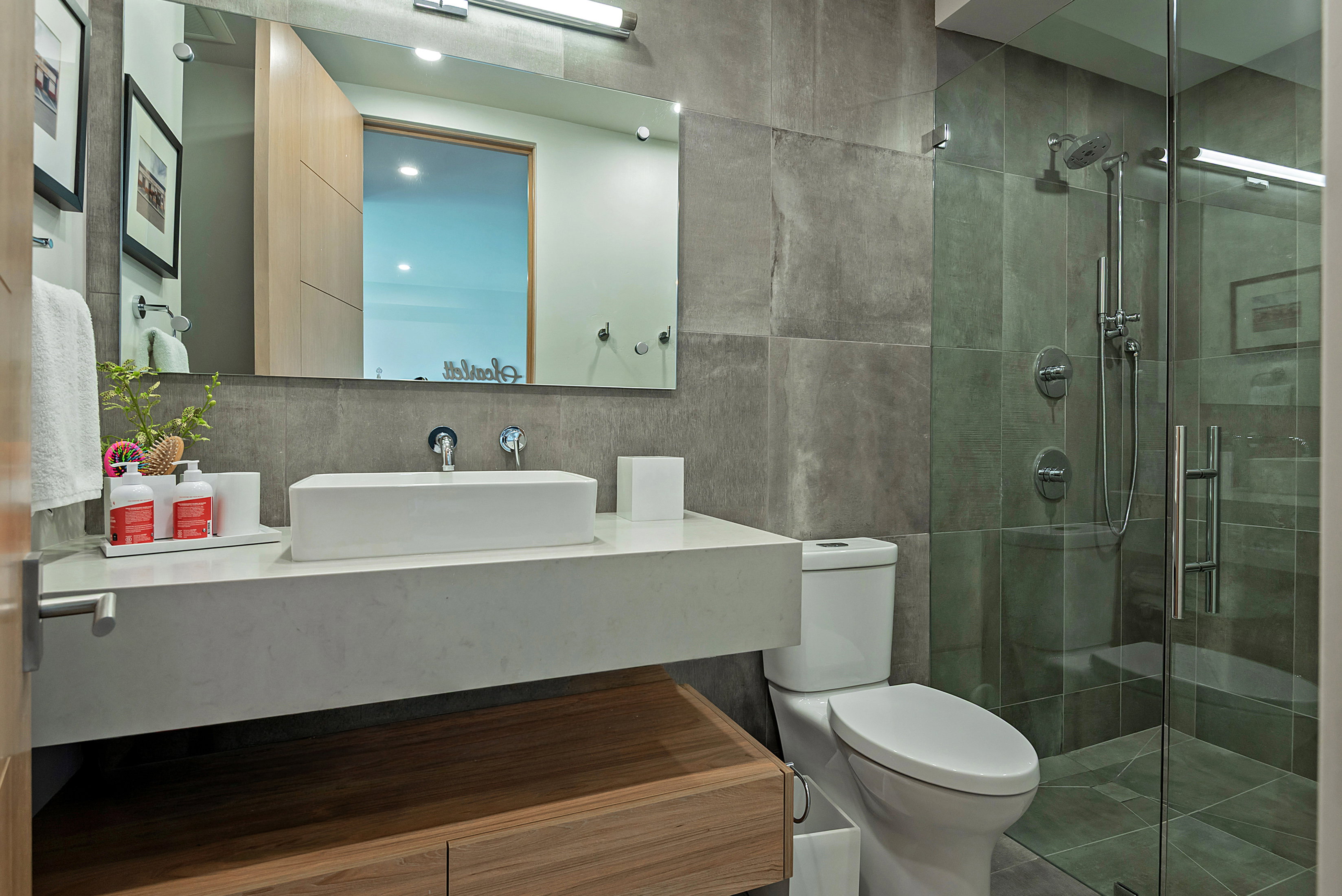 Modern bathroom featuring a rectangular vessel sink set on a floating vanity with a wood-finish base