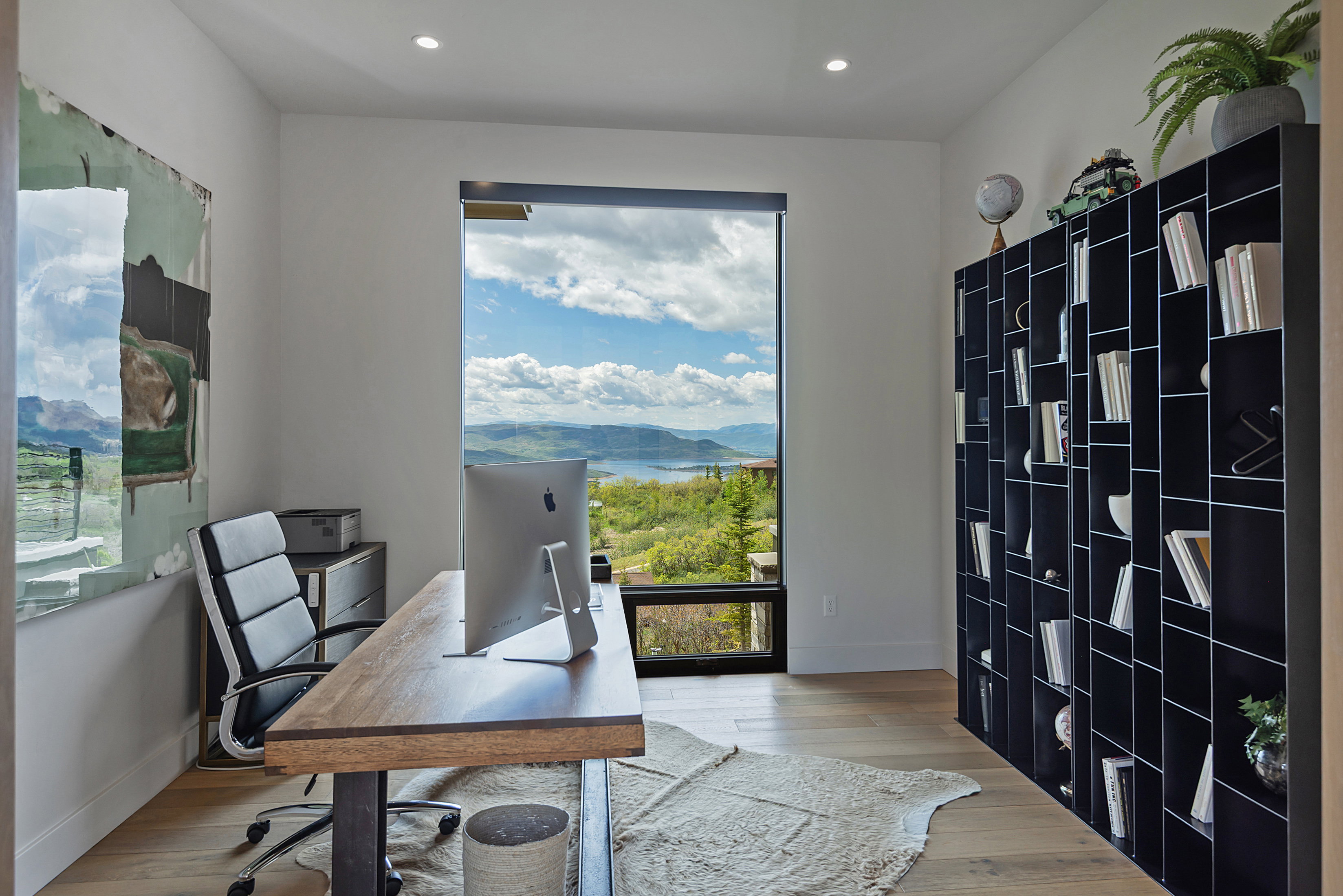 Expansive floor-to-ceiling window offering panoramic mountain and water scenery