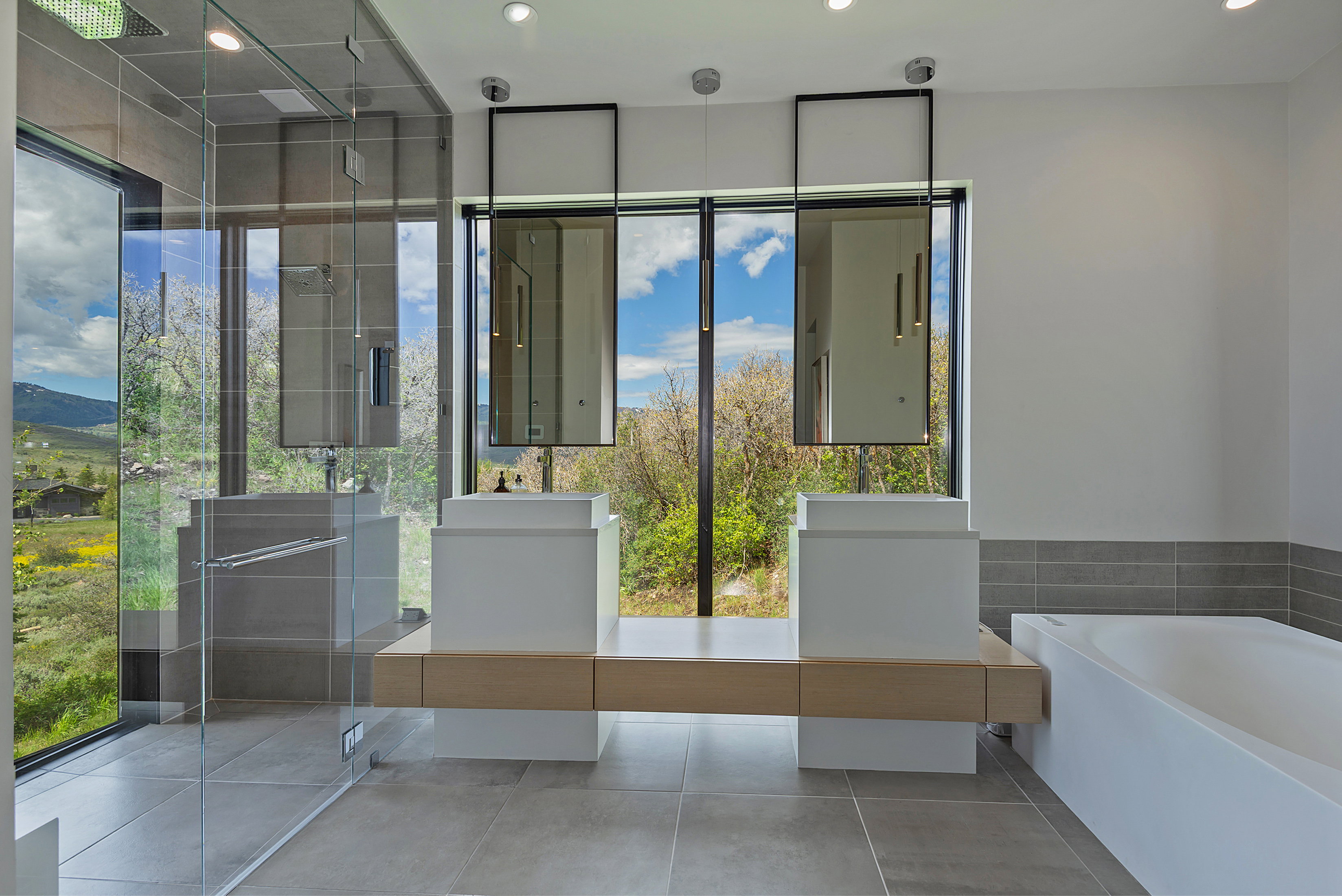 Modern bathroom featuring a double vanity with square vessel sinks, a floating wood-finish countertop, and full-height windows