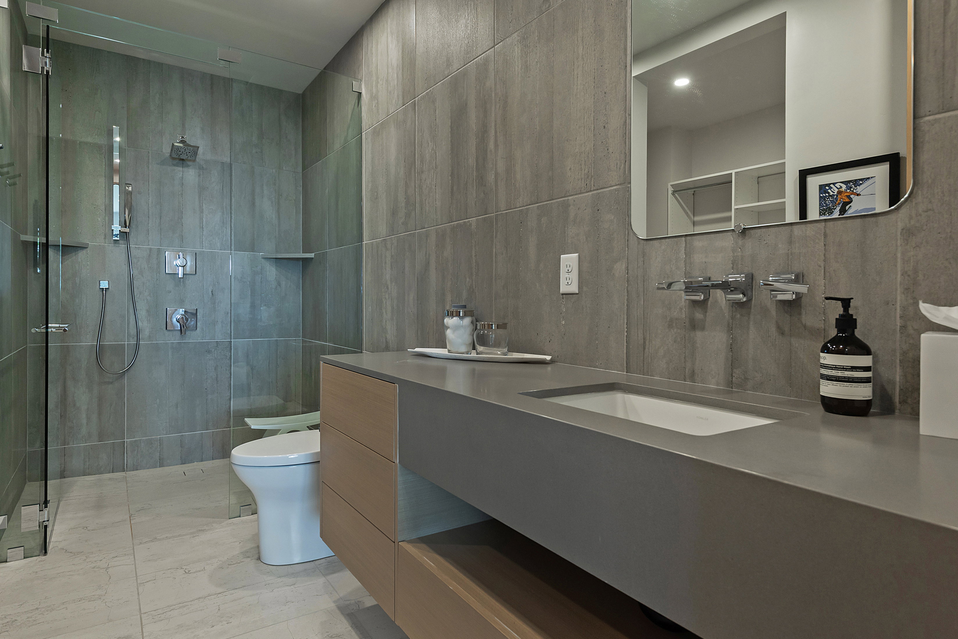 Modern bathroom featuring a floating wood-finish vanity with an integrated sink and grey countertop