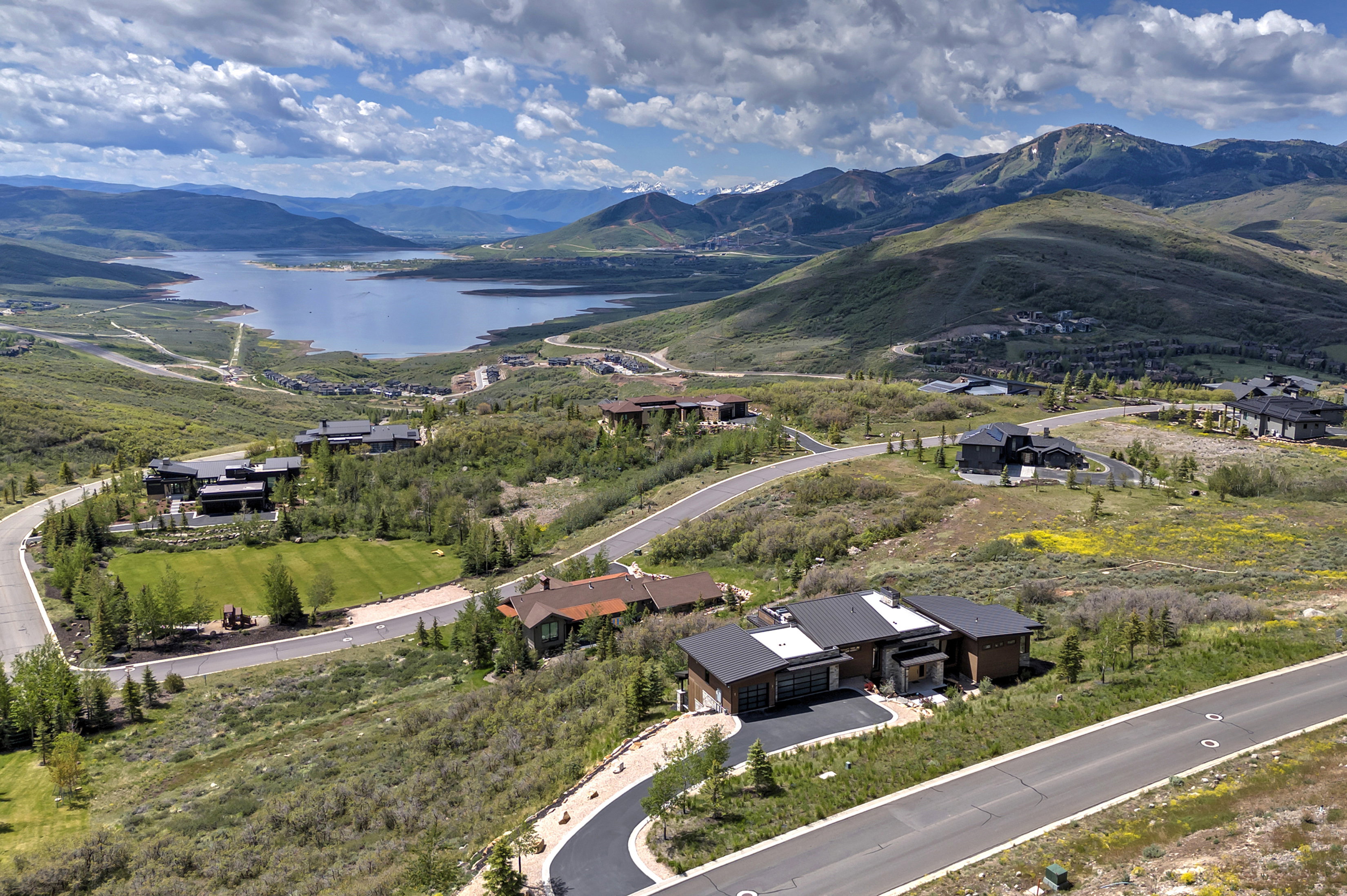 Mountainous landscape featuring a prominent lake, winding paved roads, and scattered residential properties