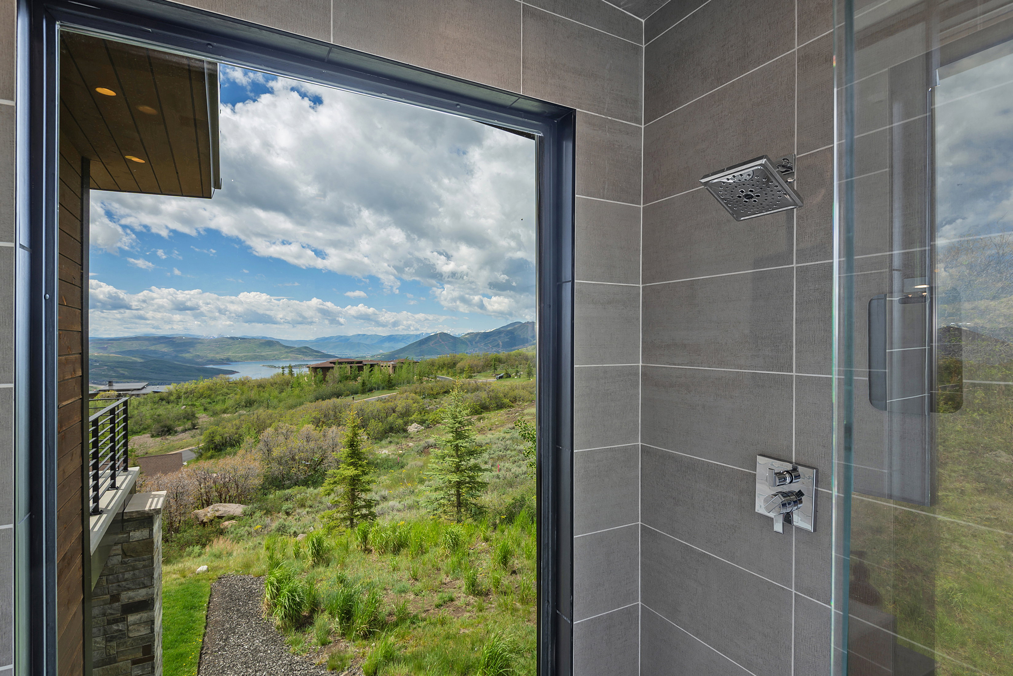 Shower with large format gray tile, glass enclosure, square rain shower head, and chrome fixtures
