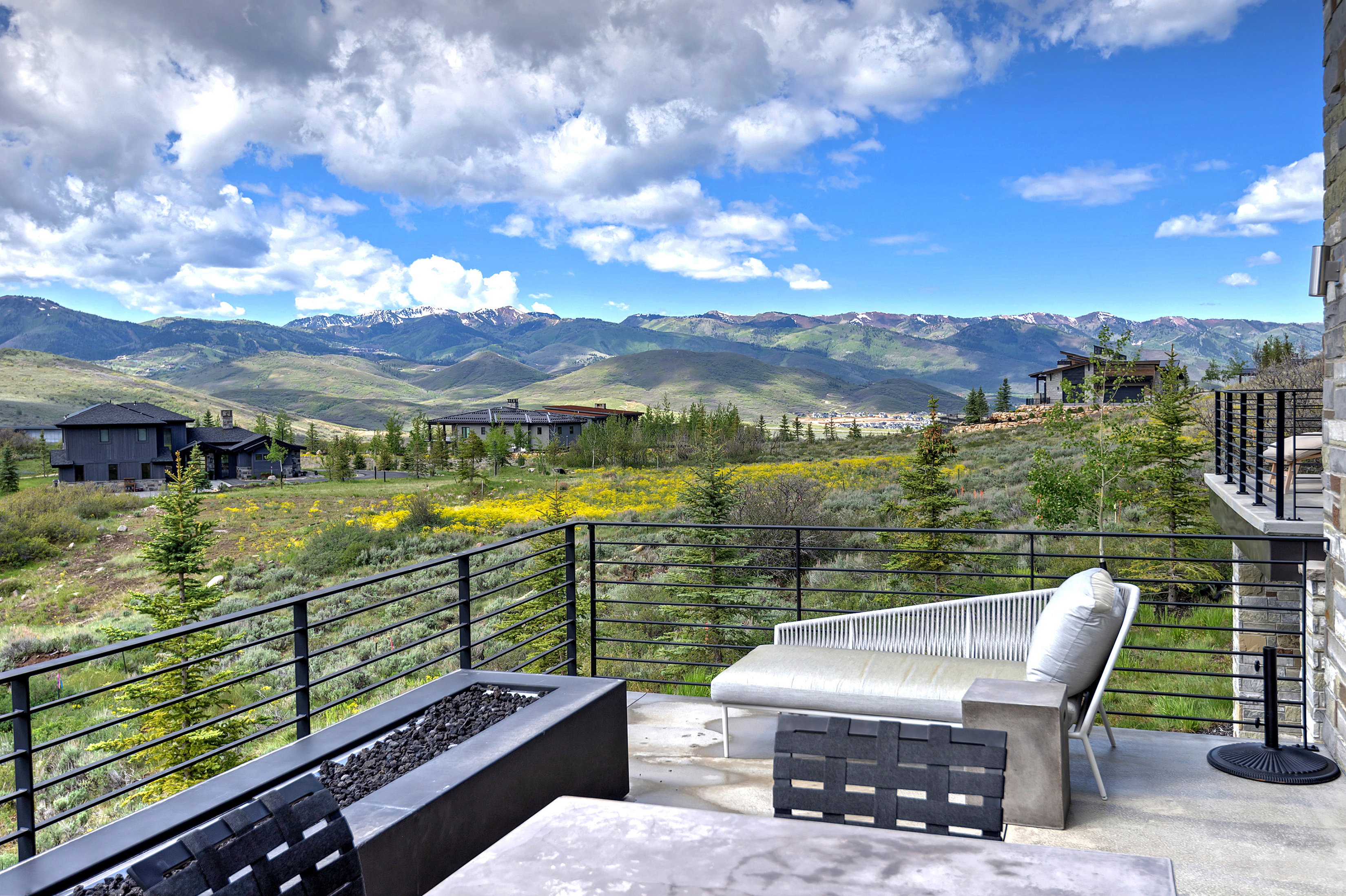 Expansive outdoor patio with a modern linear fire pit and black metal railing