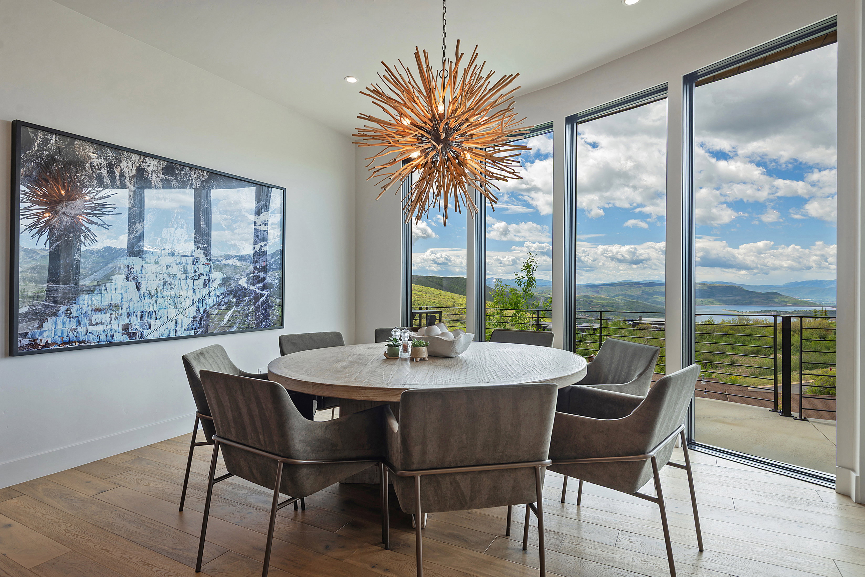 Dining area featuring expansive floor-to-ceiling windows, wood-finish flooring, and a unique branch-style chandelier