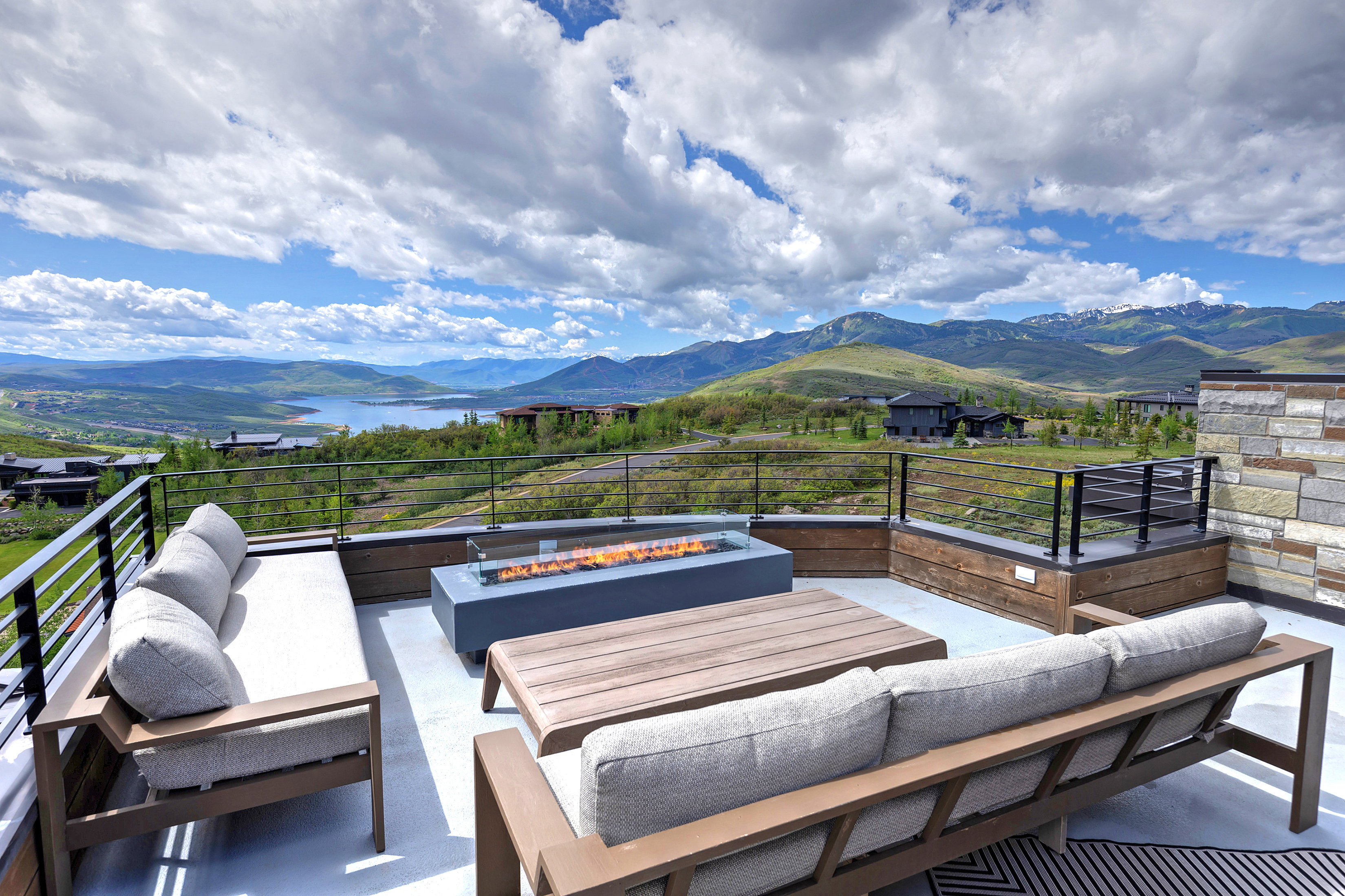 Rooftop terrace featuring a linear fire pit, composite decking, stone veneer accent wall, and horizontal cable railing
