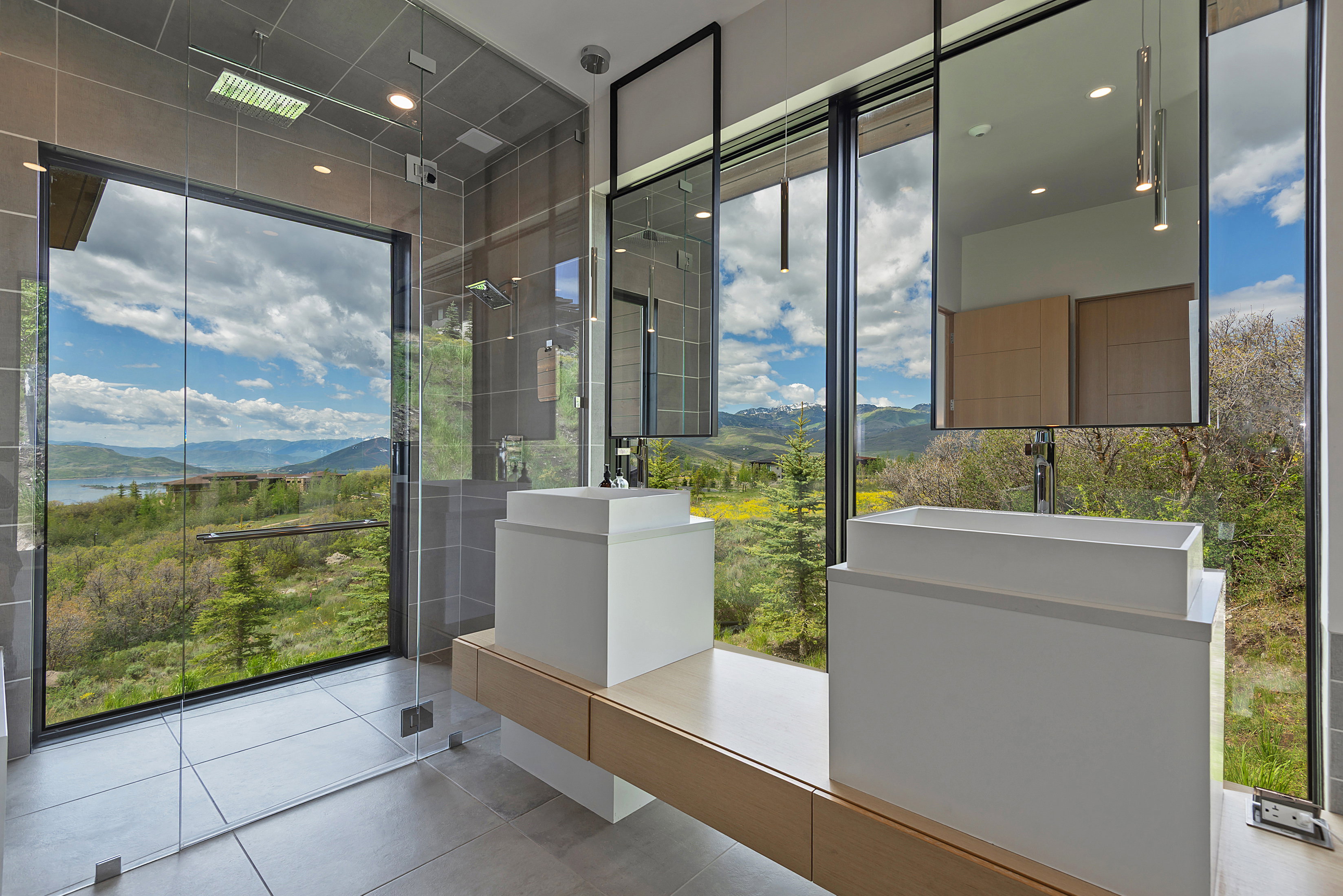 Modern bathroom featuring a floor-to-ceiling window overlooking a lake and mountains