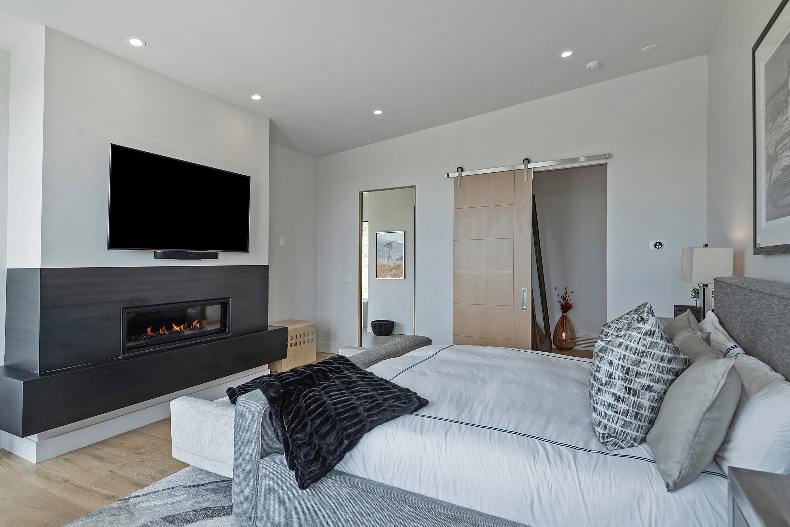 Contemporary interior featuring a linear fireplace with a dark-finish surround, recessed lighting, and a light wood-finish barn door