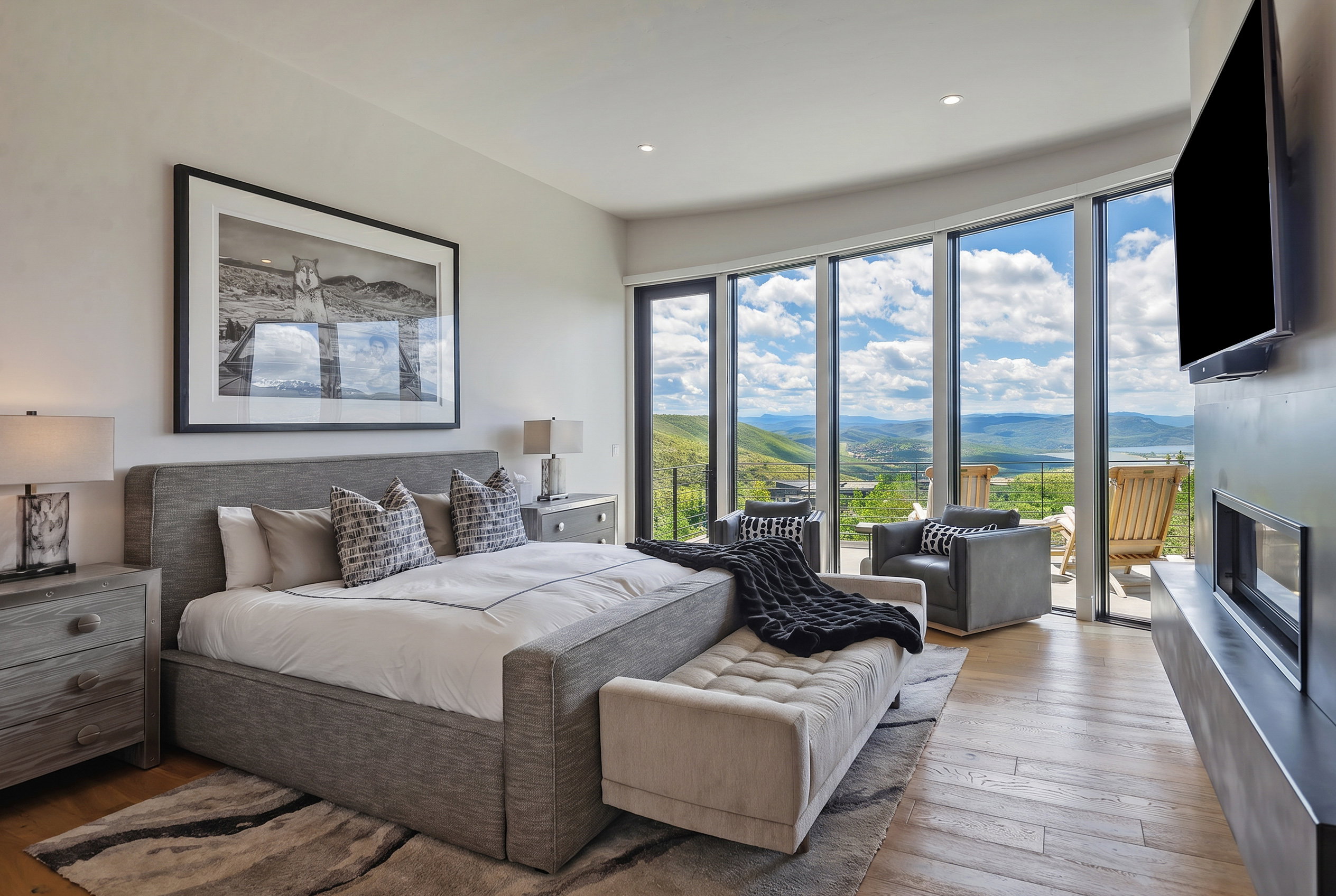 Bedroom featuring extensive floor-to-ceiling windows, wood-finish flooring, and a modern fireplace