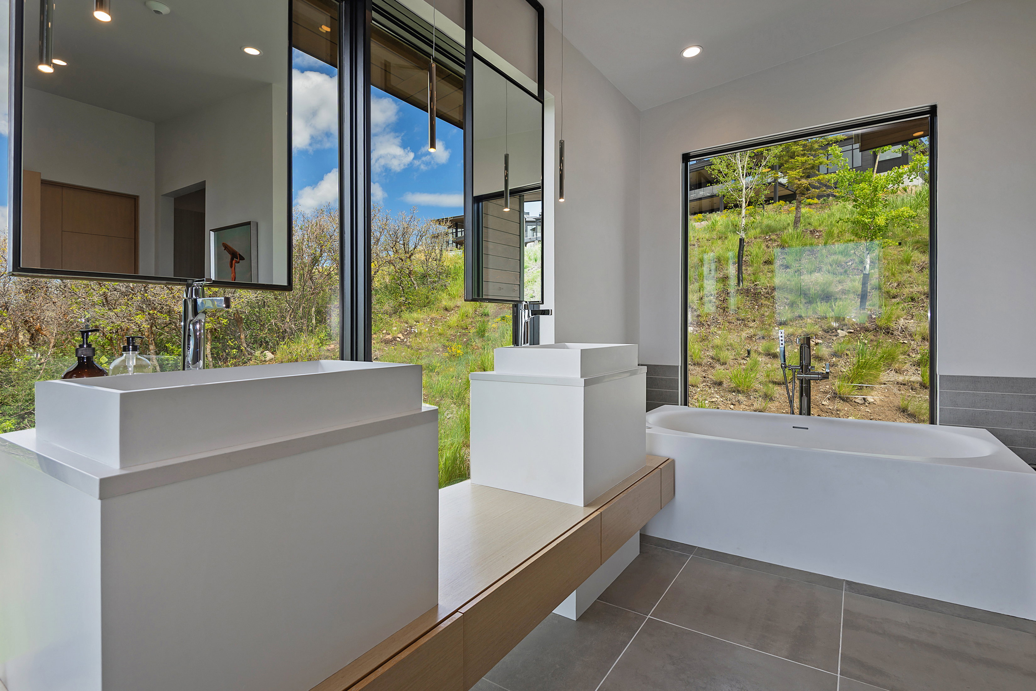Contemporary bathroom featuring dual vessel sinks on an expansive vanity with wood-finish accents