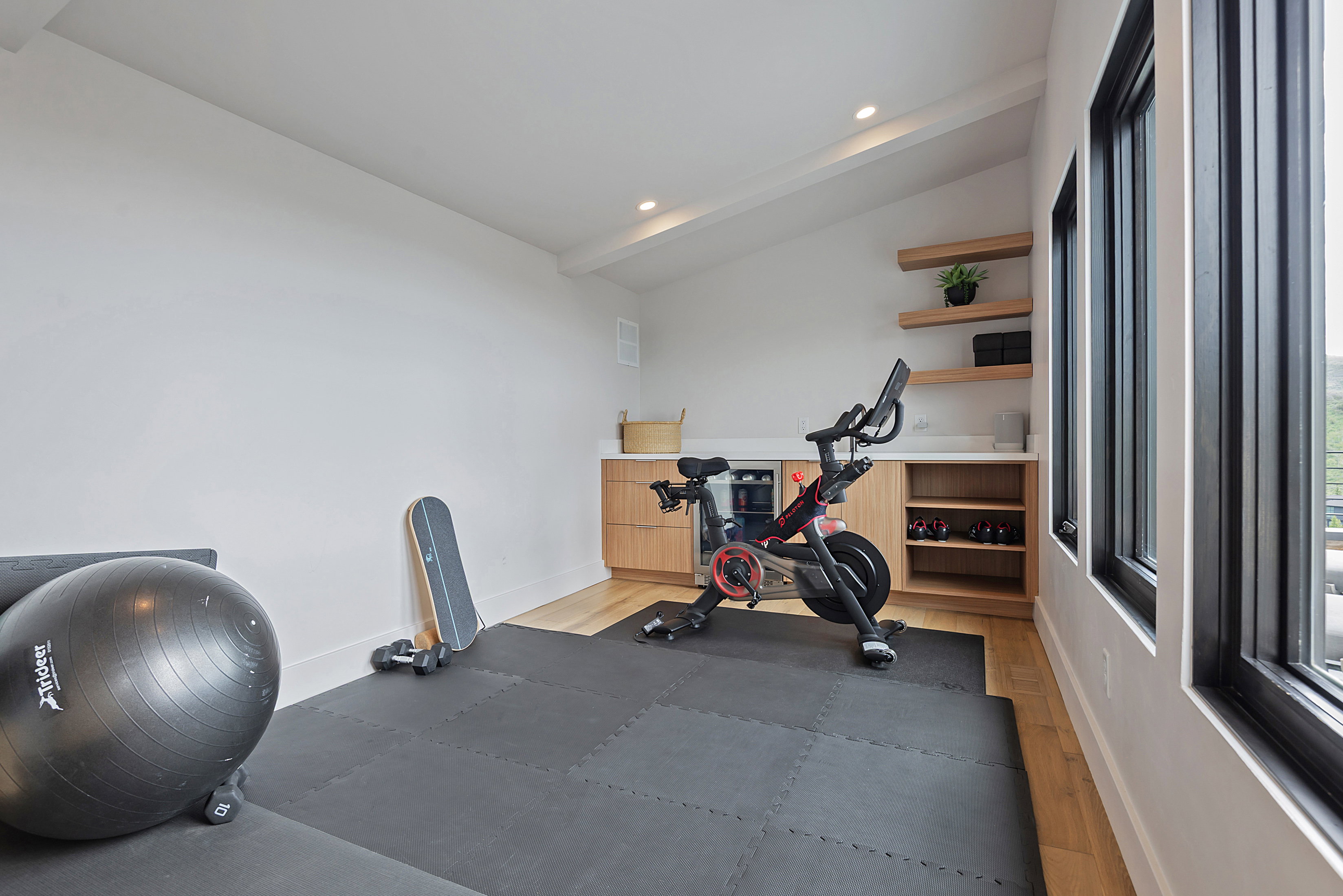 Dedicated fitness space featuring light wood-finish flooring, built-in cabinetry with a light-toned countertop, and recessed lighting
