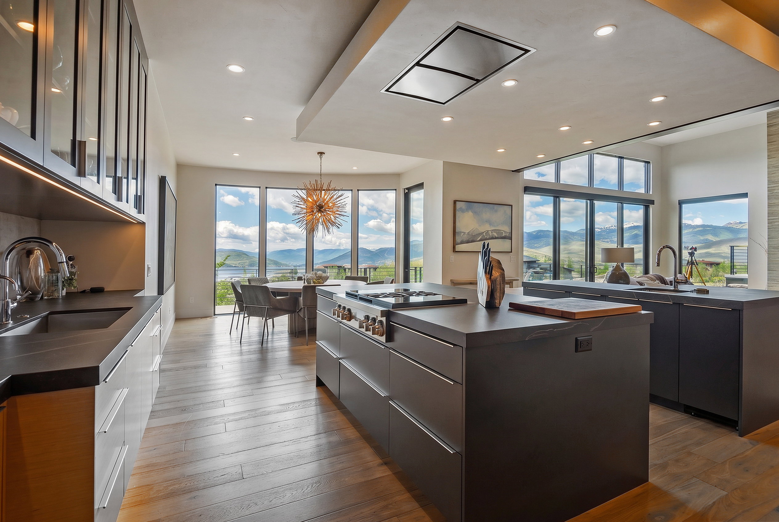 Modern kitchen featuring wood-finish flooring and extensive dark-toned flat-panel cabinetry