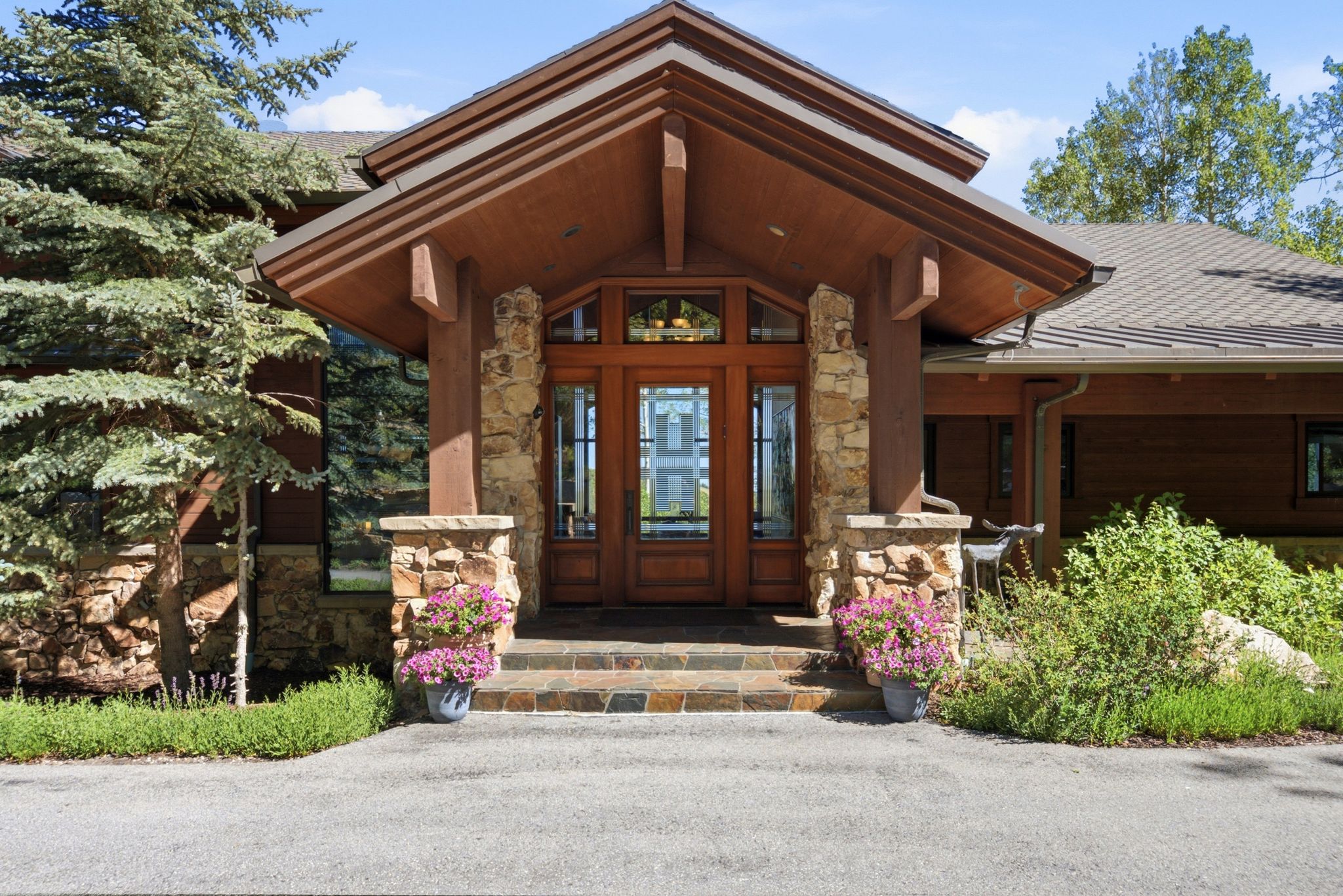 Grand entrance featuring a wood-panel door with sidelights, stone columns, and a covered porch