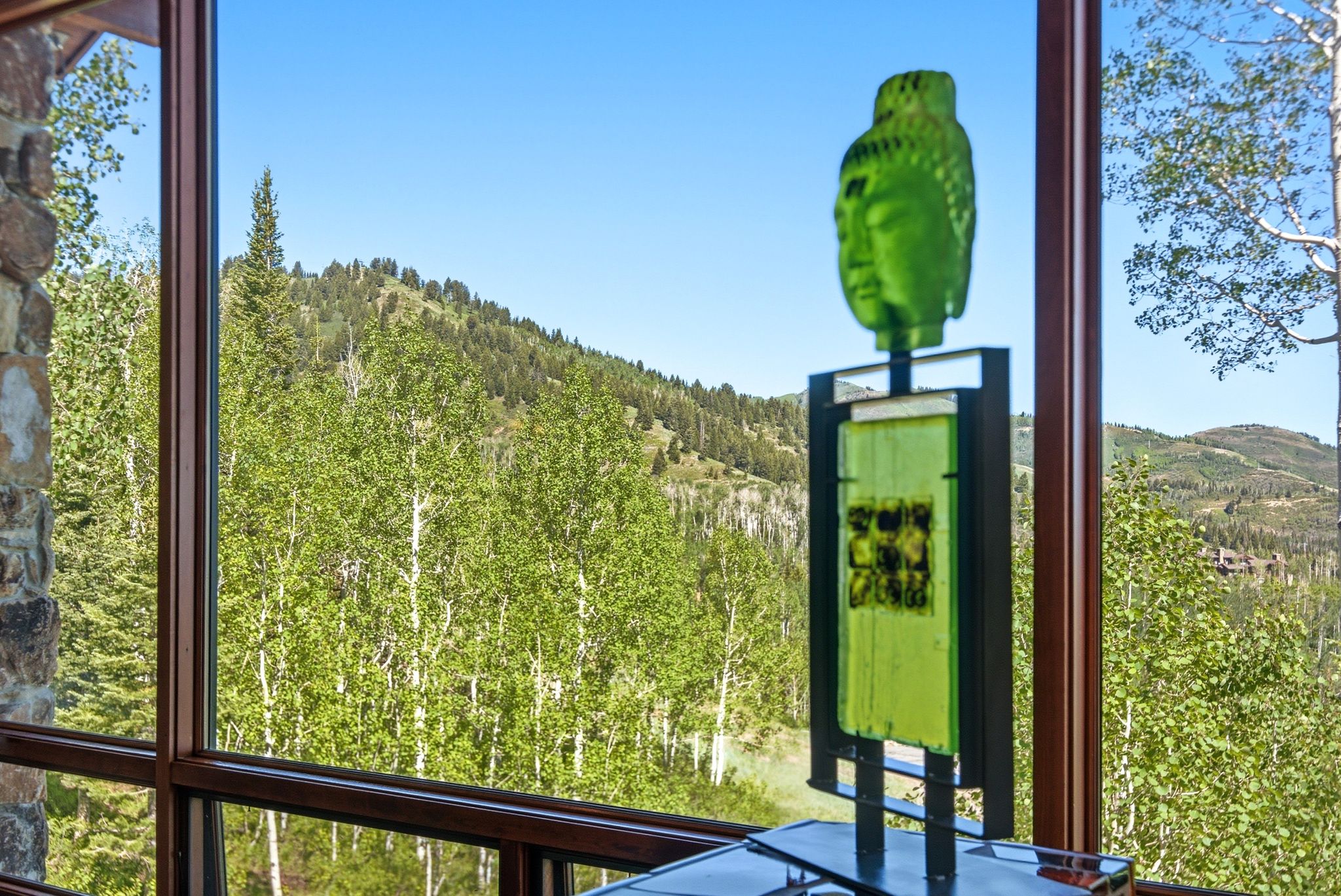 Expansive window framing a mountain landscape with abundant trees