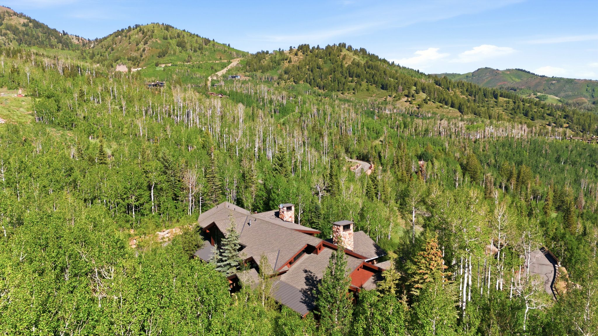 Expansive mountain setting featuring a multi-level residence with a gabled roofline and stone chimney