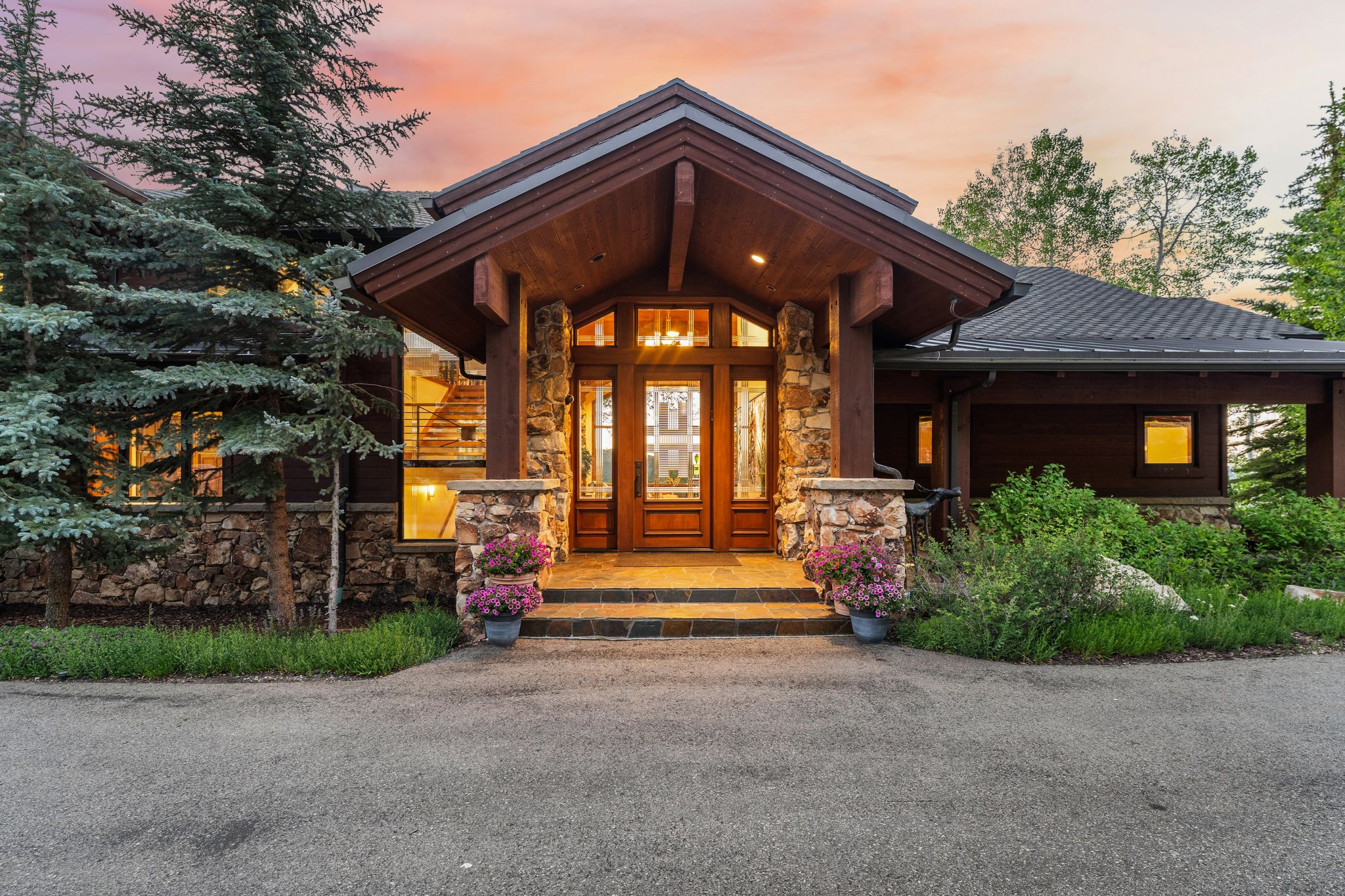 Stone and wood-clad exterior with a covered entry, featuring a wood front door with sidelight windows, and stone columns