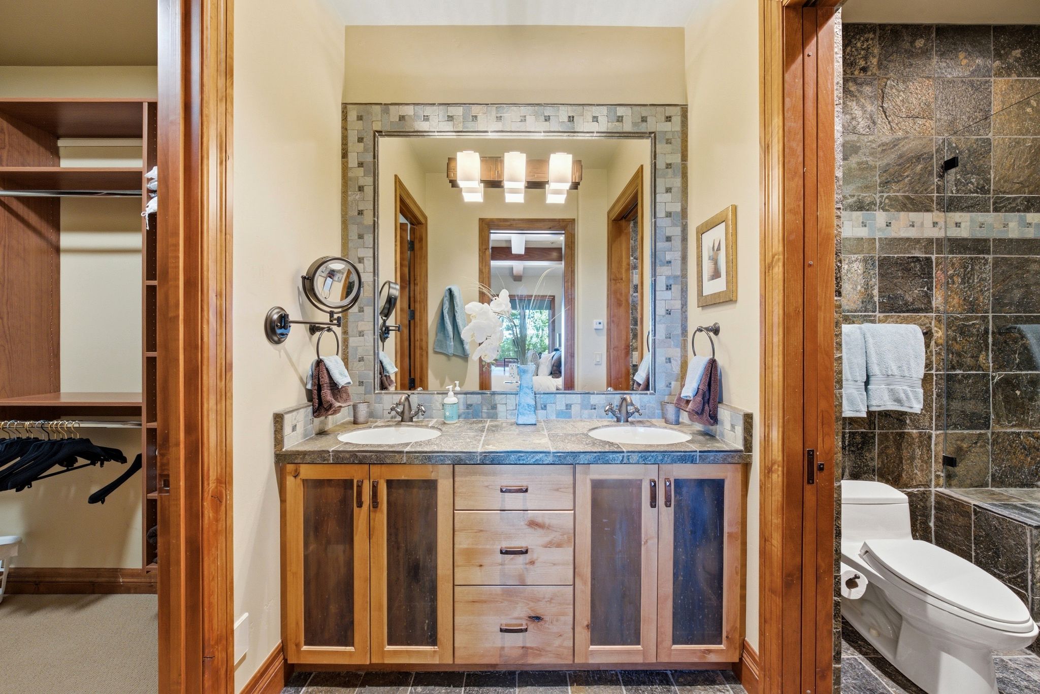Dual vanity with a stone countertop and integrated sinks, illuminated by a multi-bulb fixture