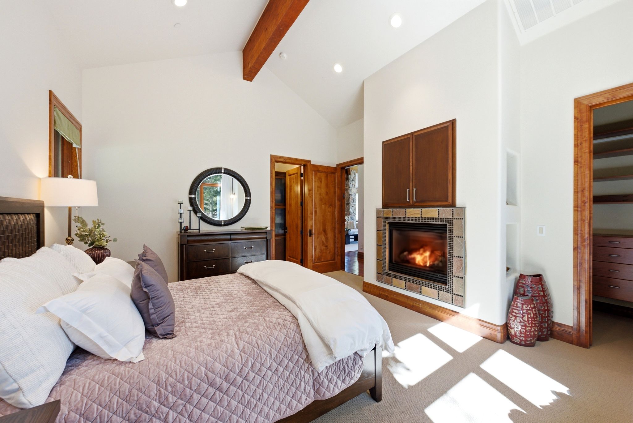 Vaulted ceiling with exposed wood beam, recessed lighting, and a built-in fireplace with stone surround