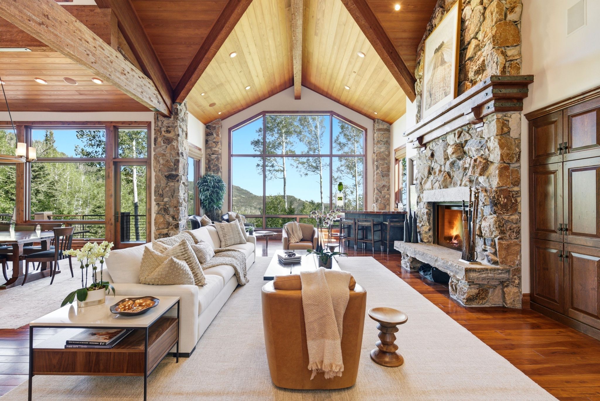 Great room with vaulted wood-paneled ceilings, exposed wood beams, and extensive stone accents